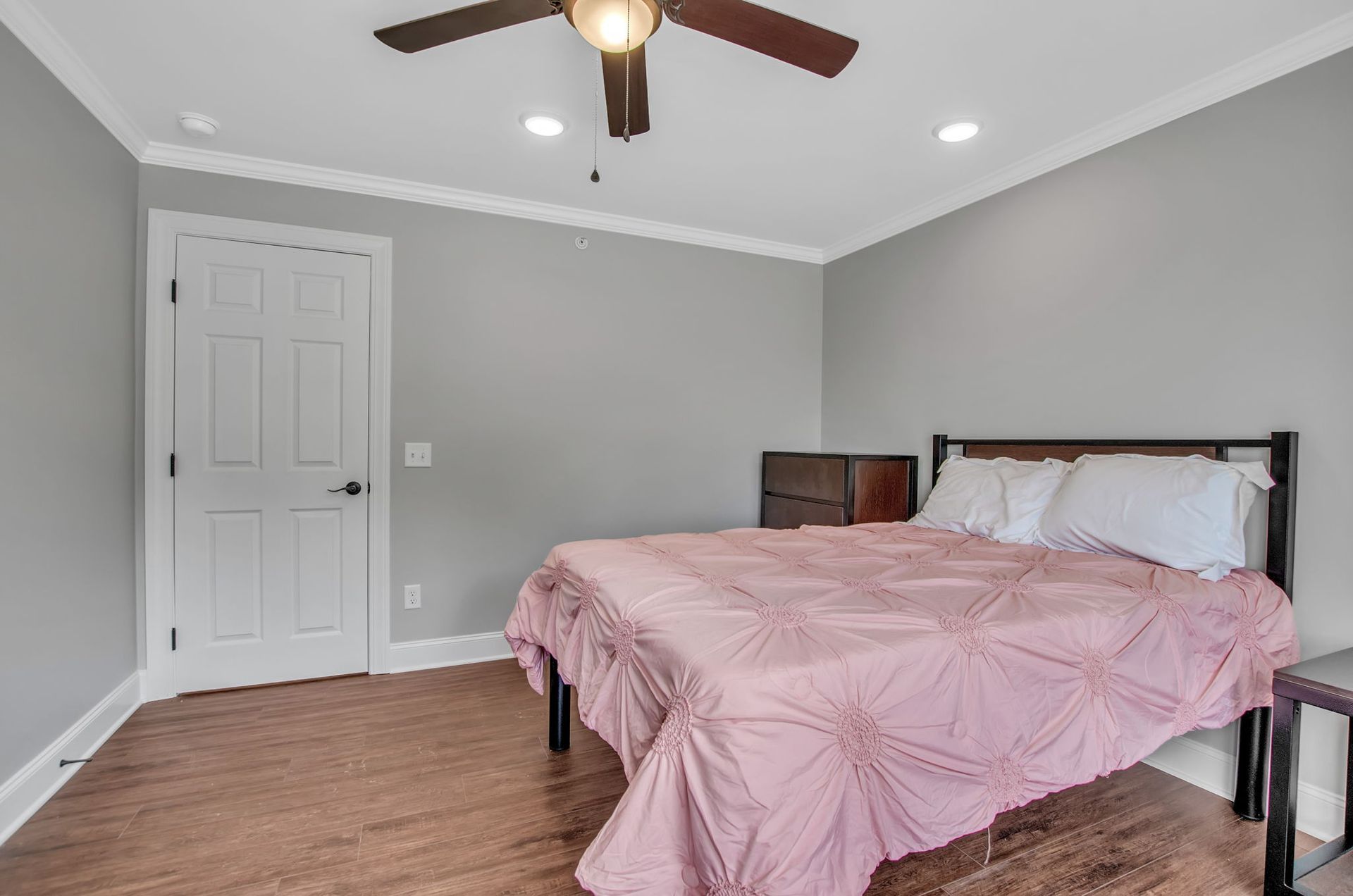 A bedroom with a bed and a ceiling fan.