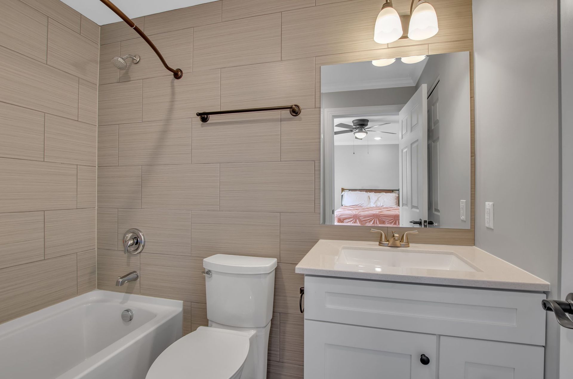 A bathroom with a toilet , sink , bathtub and mirror.