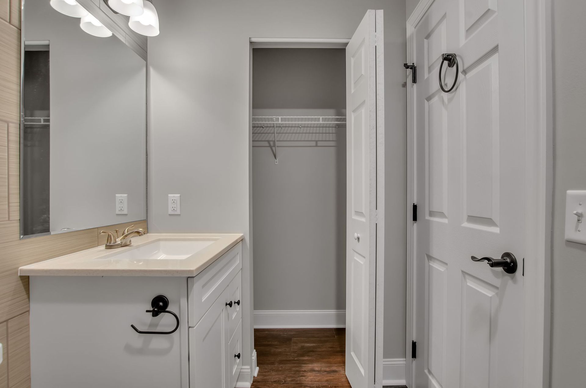 A bathroom with a sink , mirror , and closet.