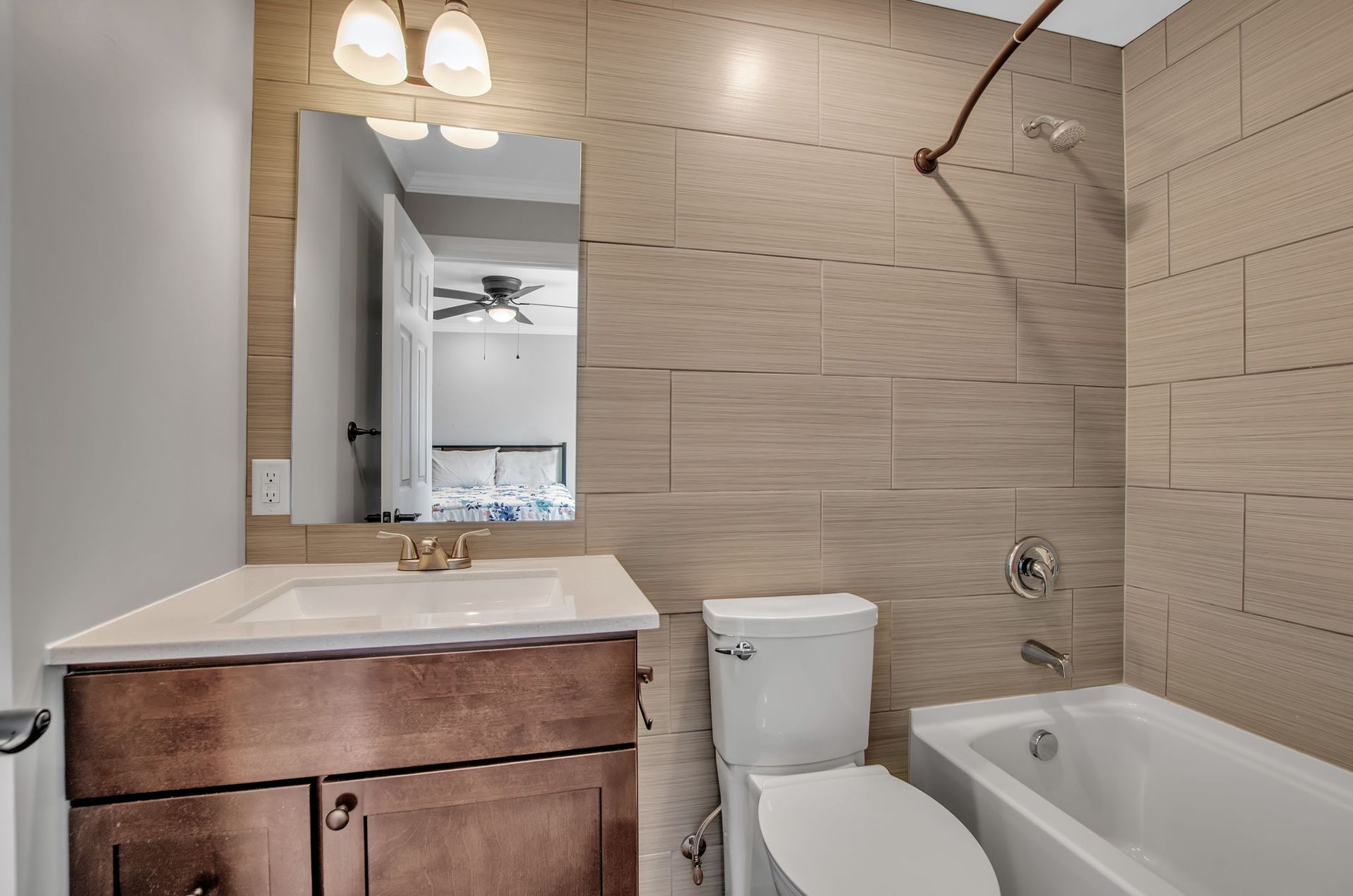 A bathroom with a toilet , sink , tub and mirror.