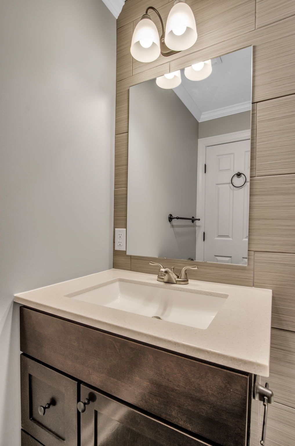 A bathroom with a sink , mirror and light fixtures.