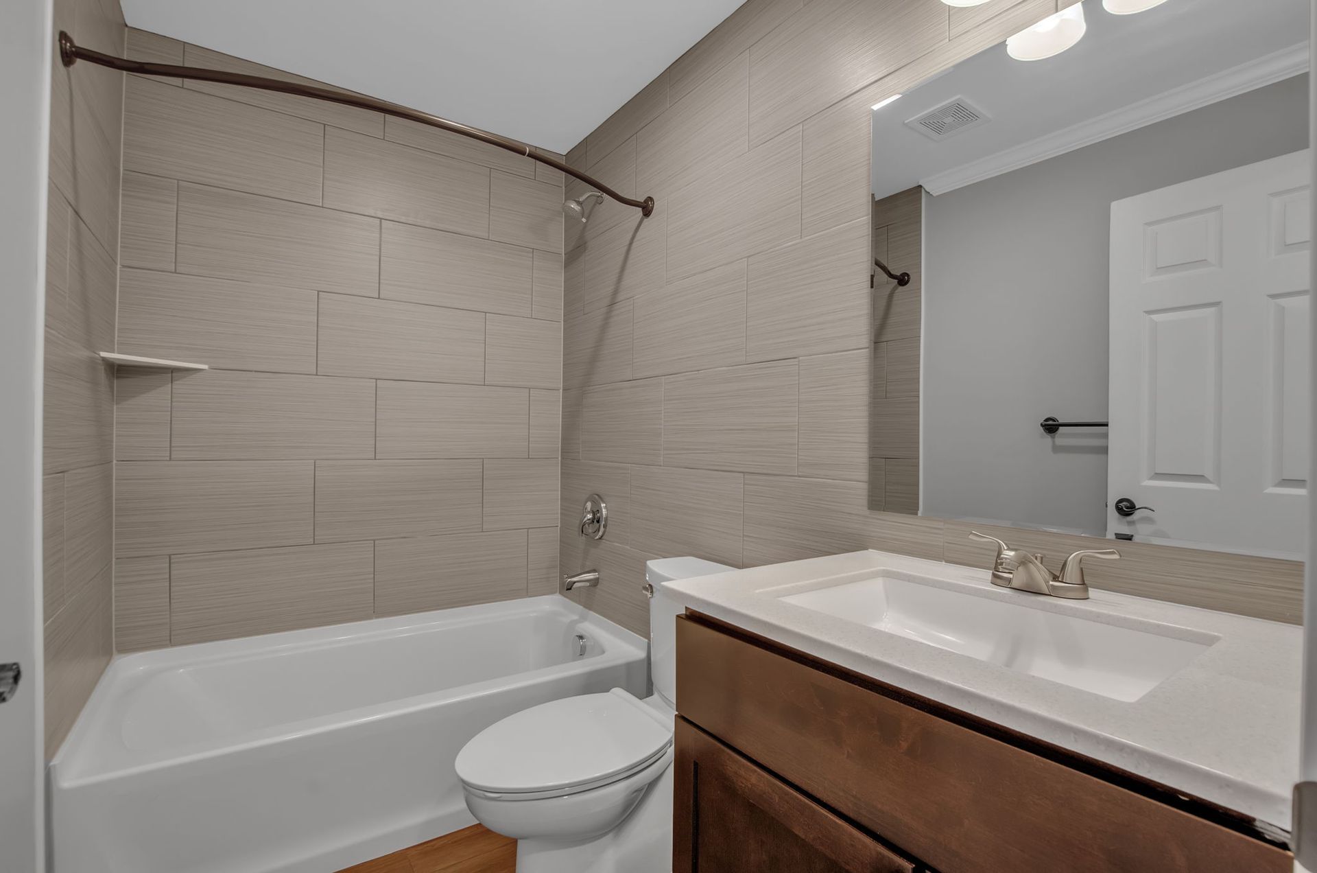 A bathroom with a toilet , sink , bathtub and mirror.