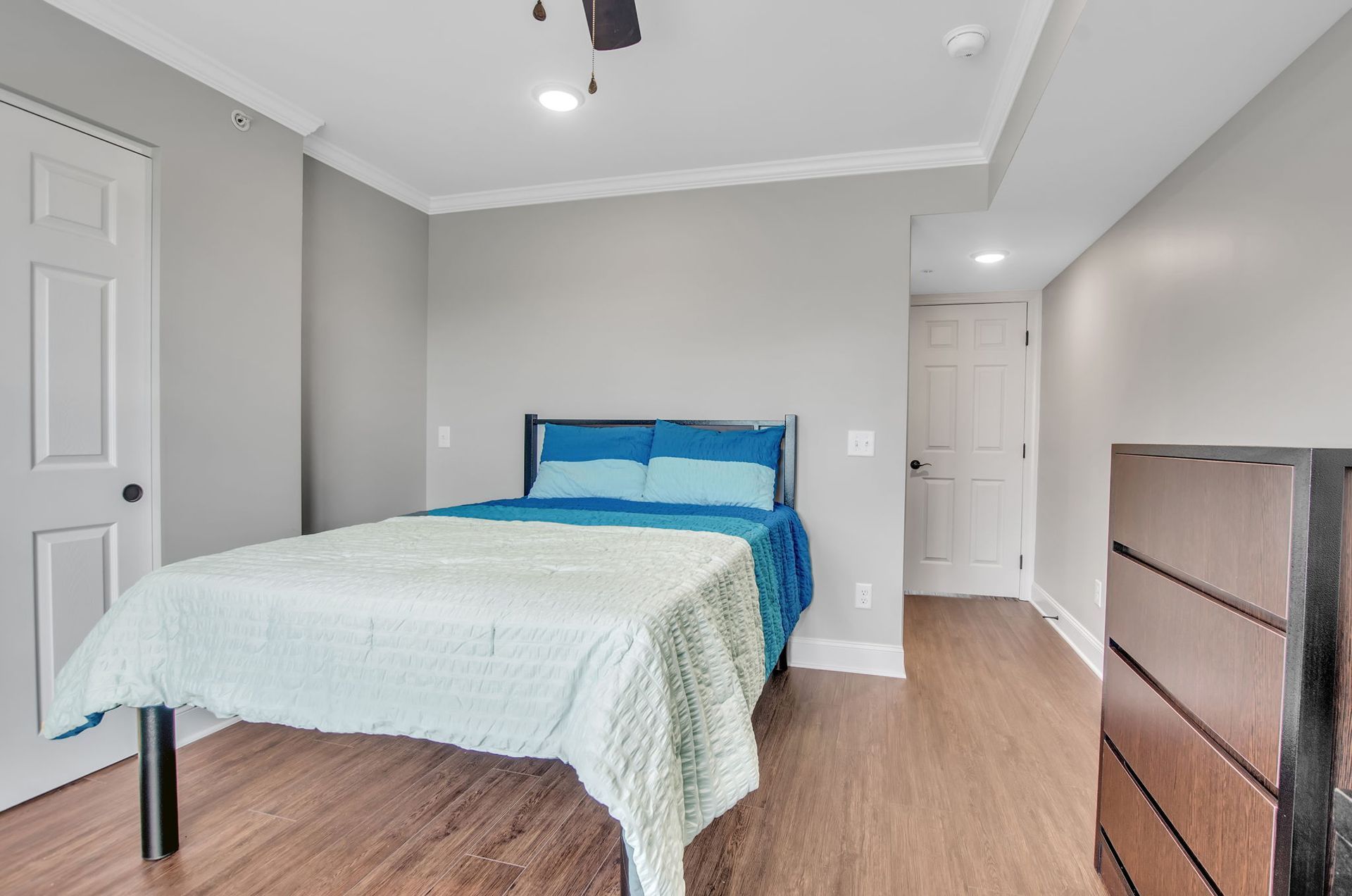A bedroom with a bed , dresser , and ceiling fan.