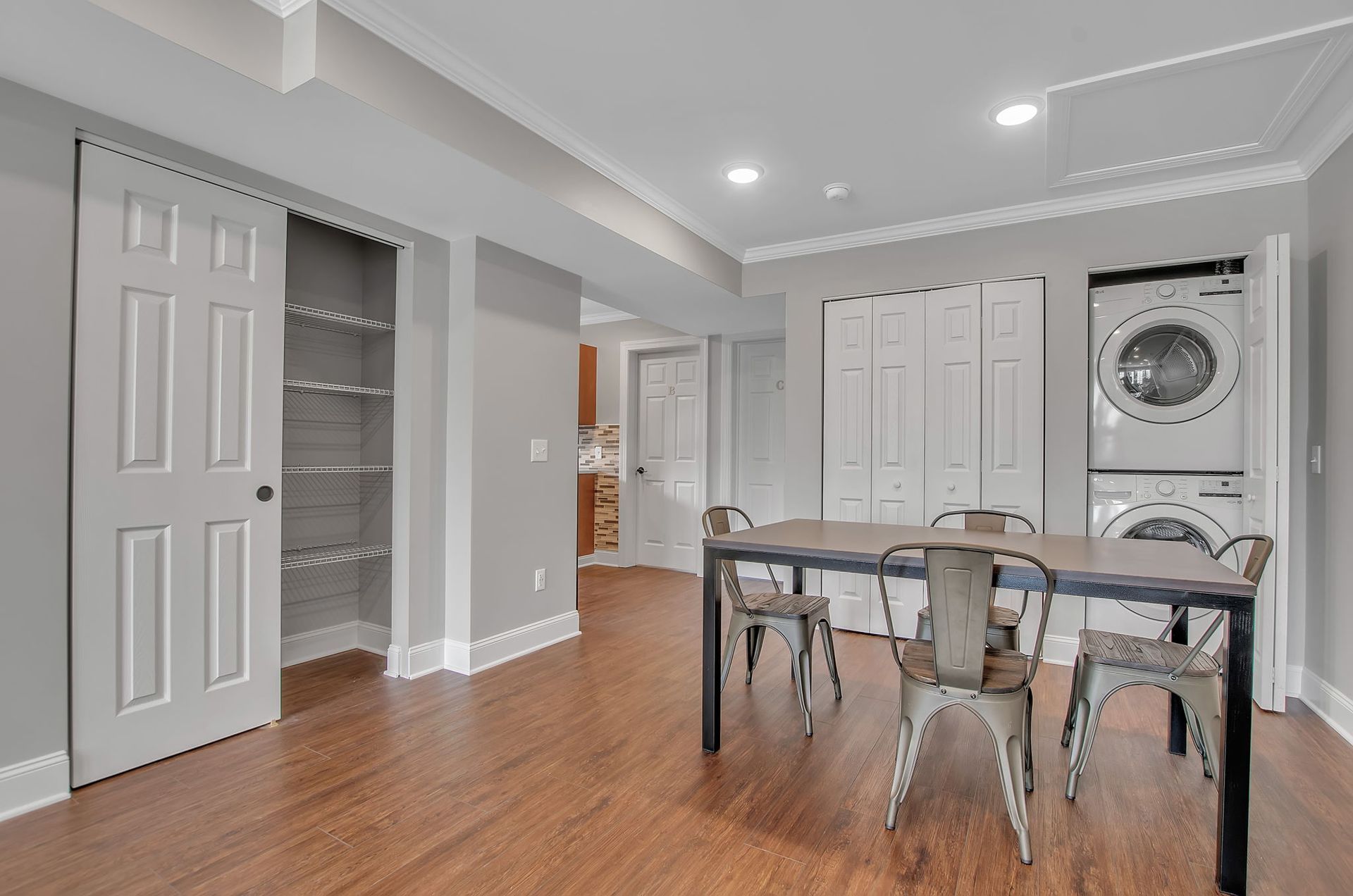 A dining room with a table and chairs and a washer and dryer stacked on top of each other.