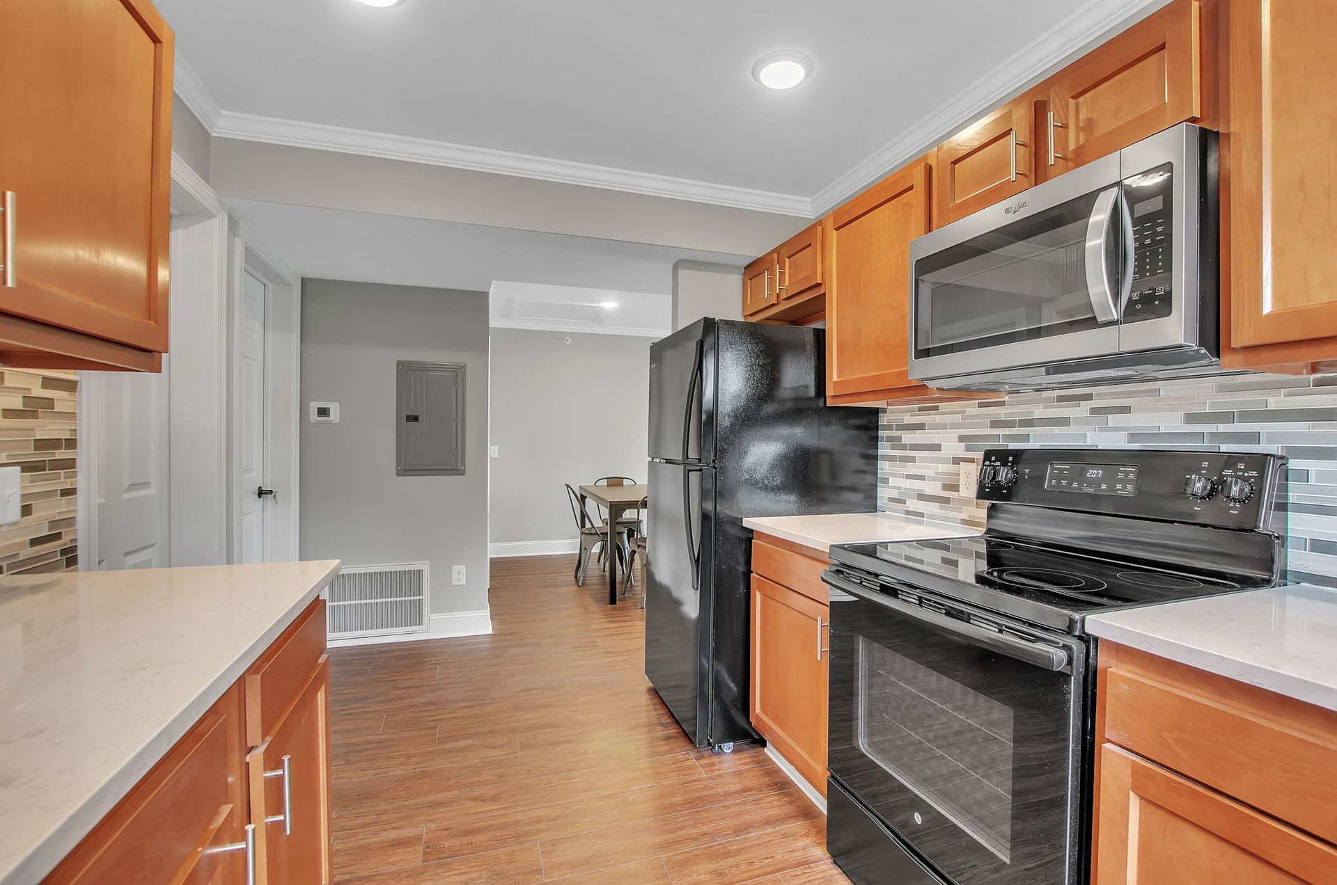 A kitchen with wooden cabinets , stainless steel appliances , and a refrigerator.