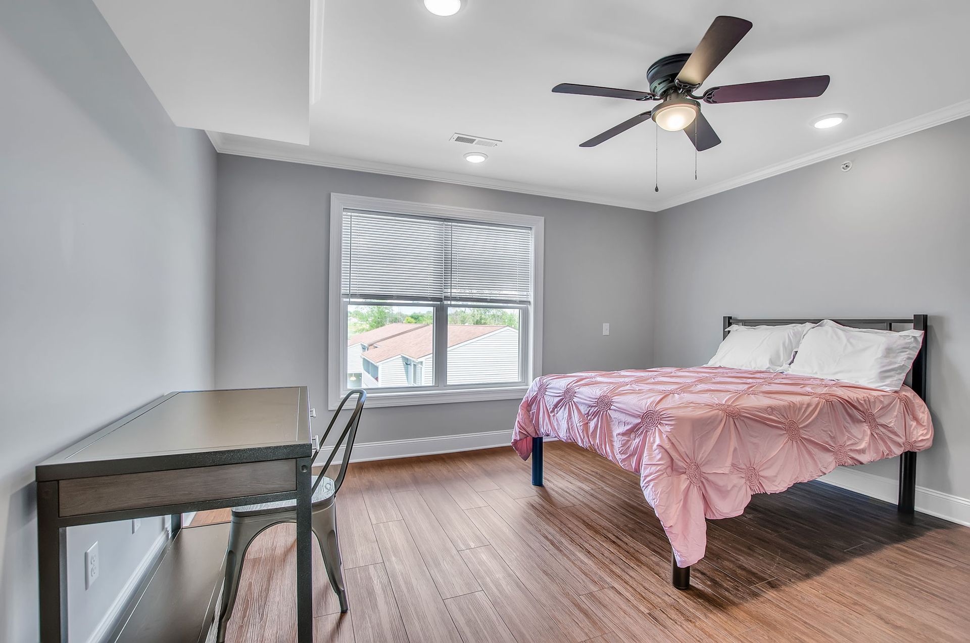 A bedroom with a bed , desk , chair and ceiling fan.