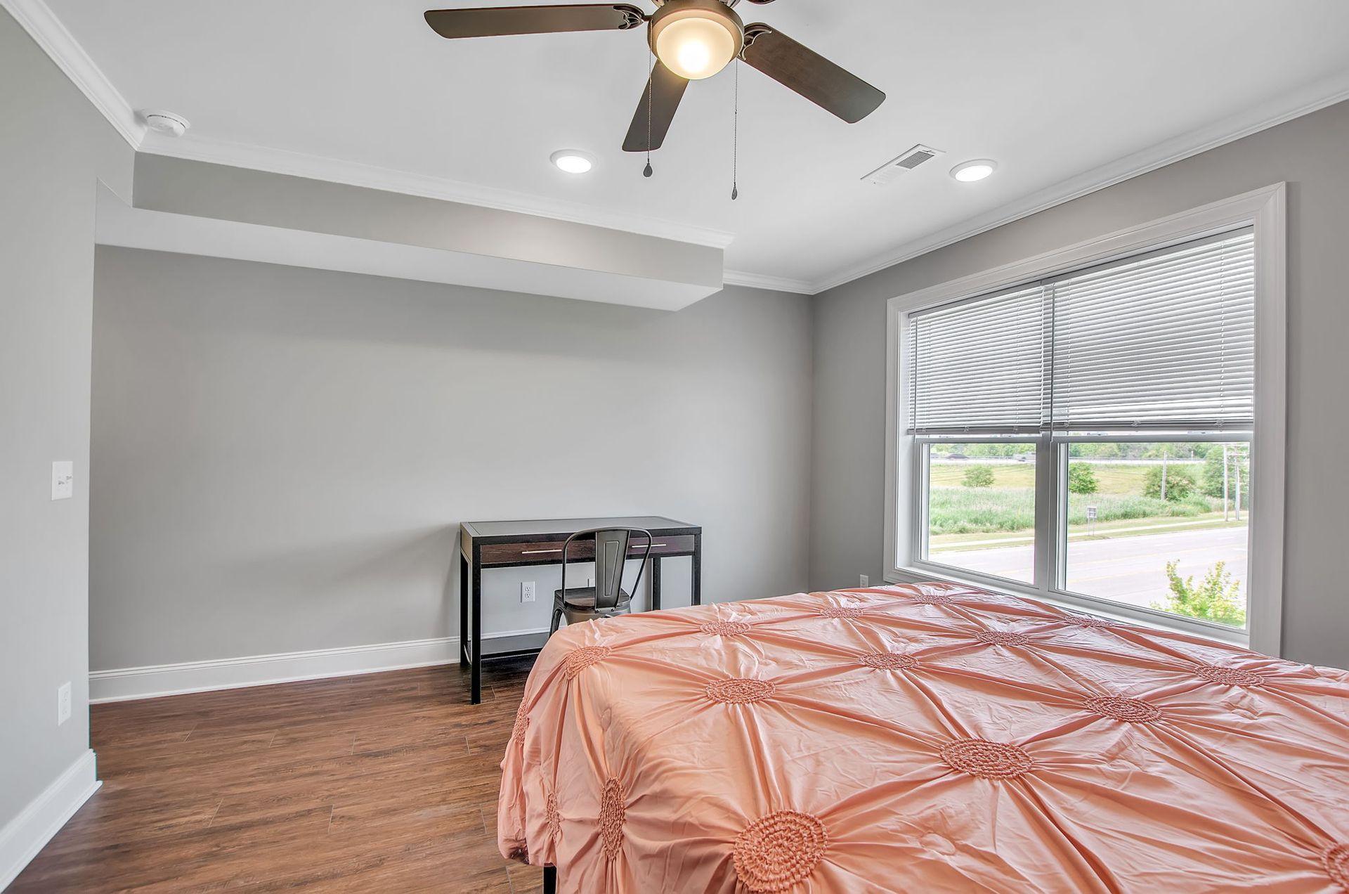 A bedroom with two beds , a desk and a ceiling fan.
