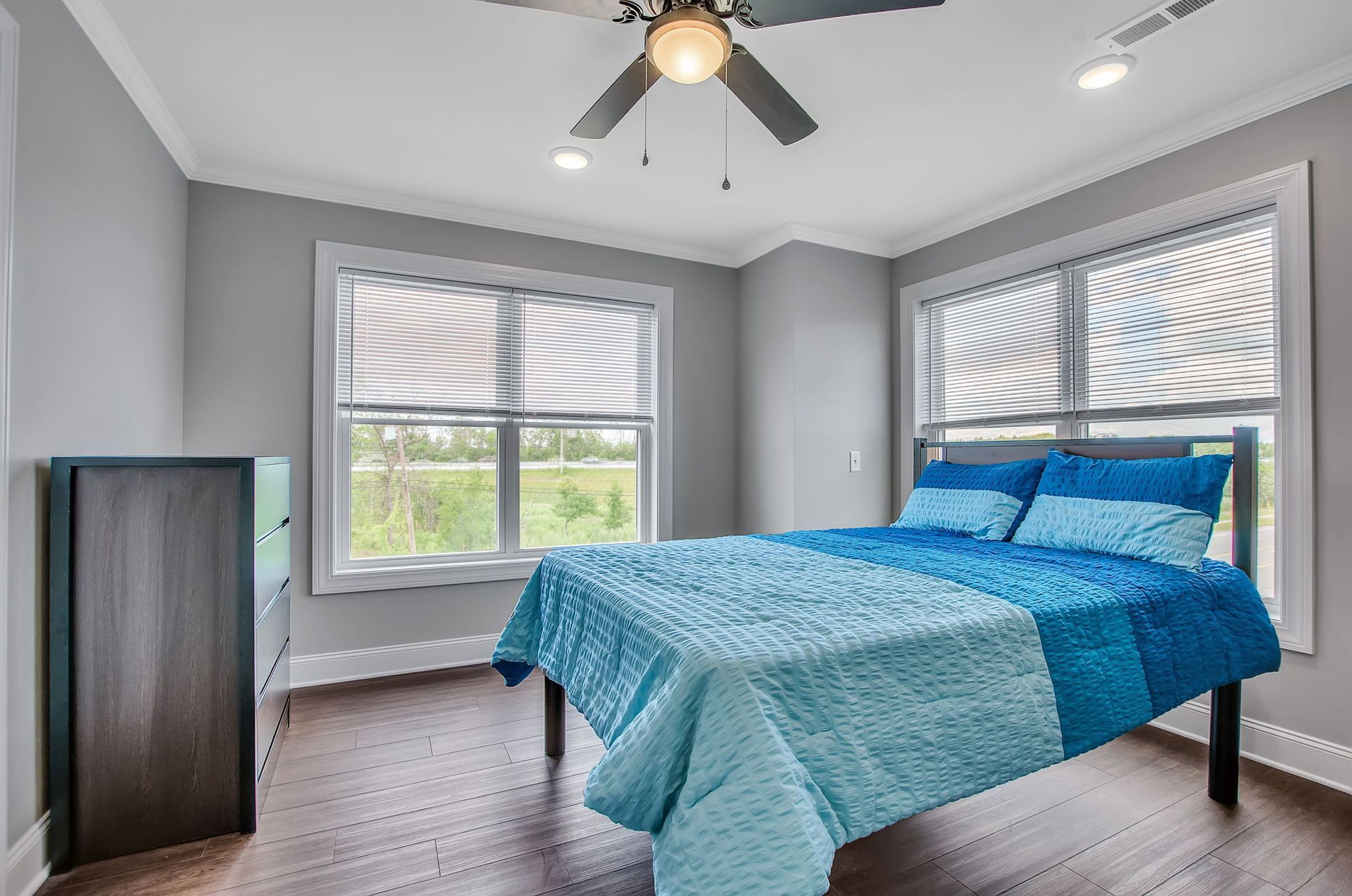 A bedroom with a bed , dresser , and ceiling fan.