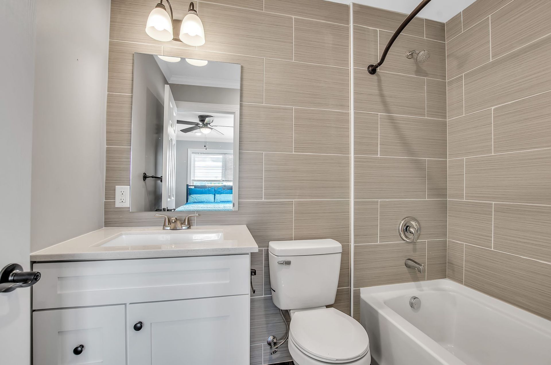 A bathroom with a toilet , sink , tub and mirror.