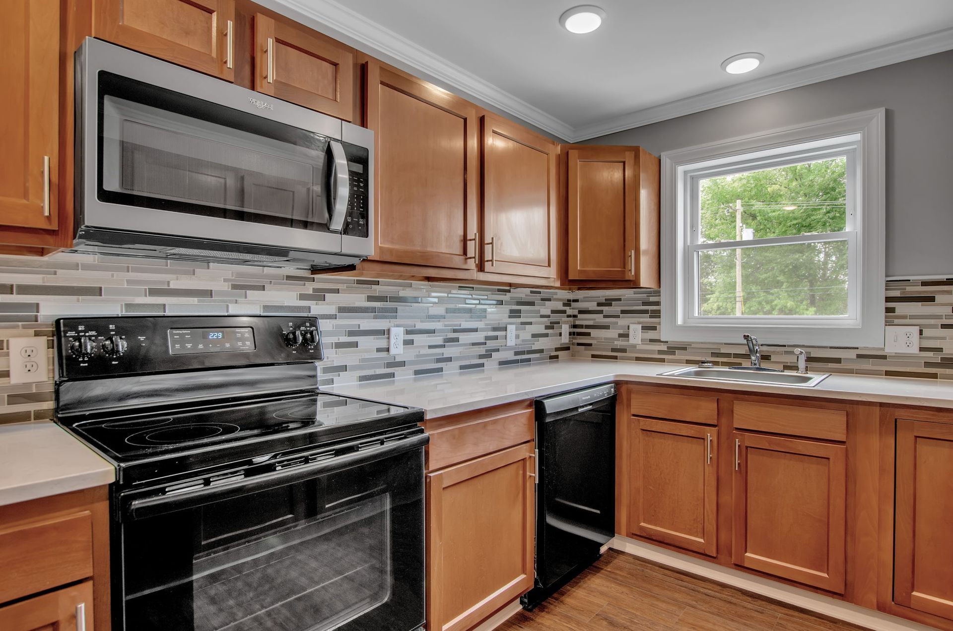 A kitchen with wooden cabinets , a stove , a microwave , and a sink.