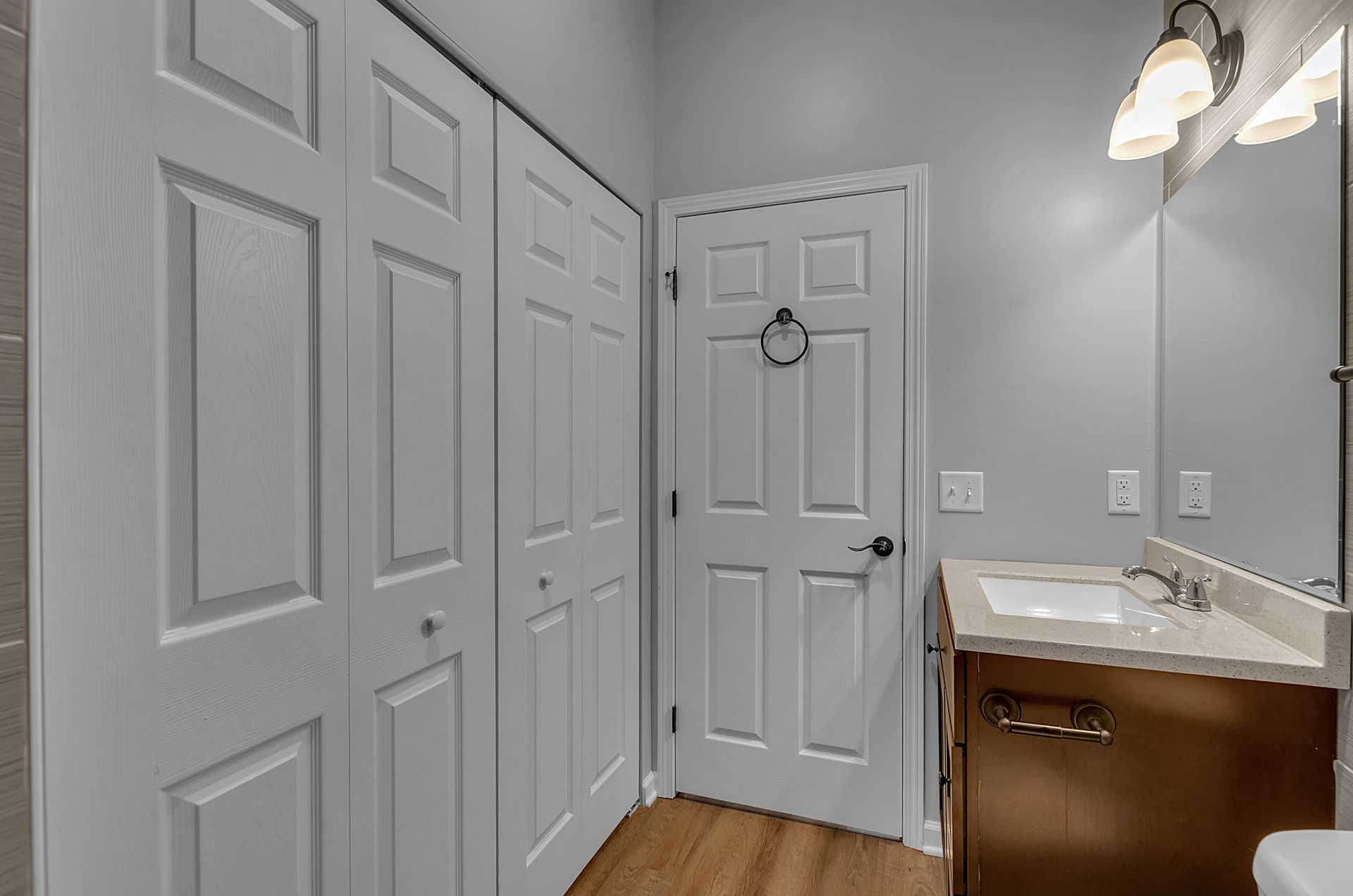 A bathroom with a sink , mirror and closet.