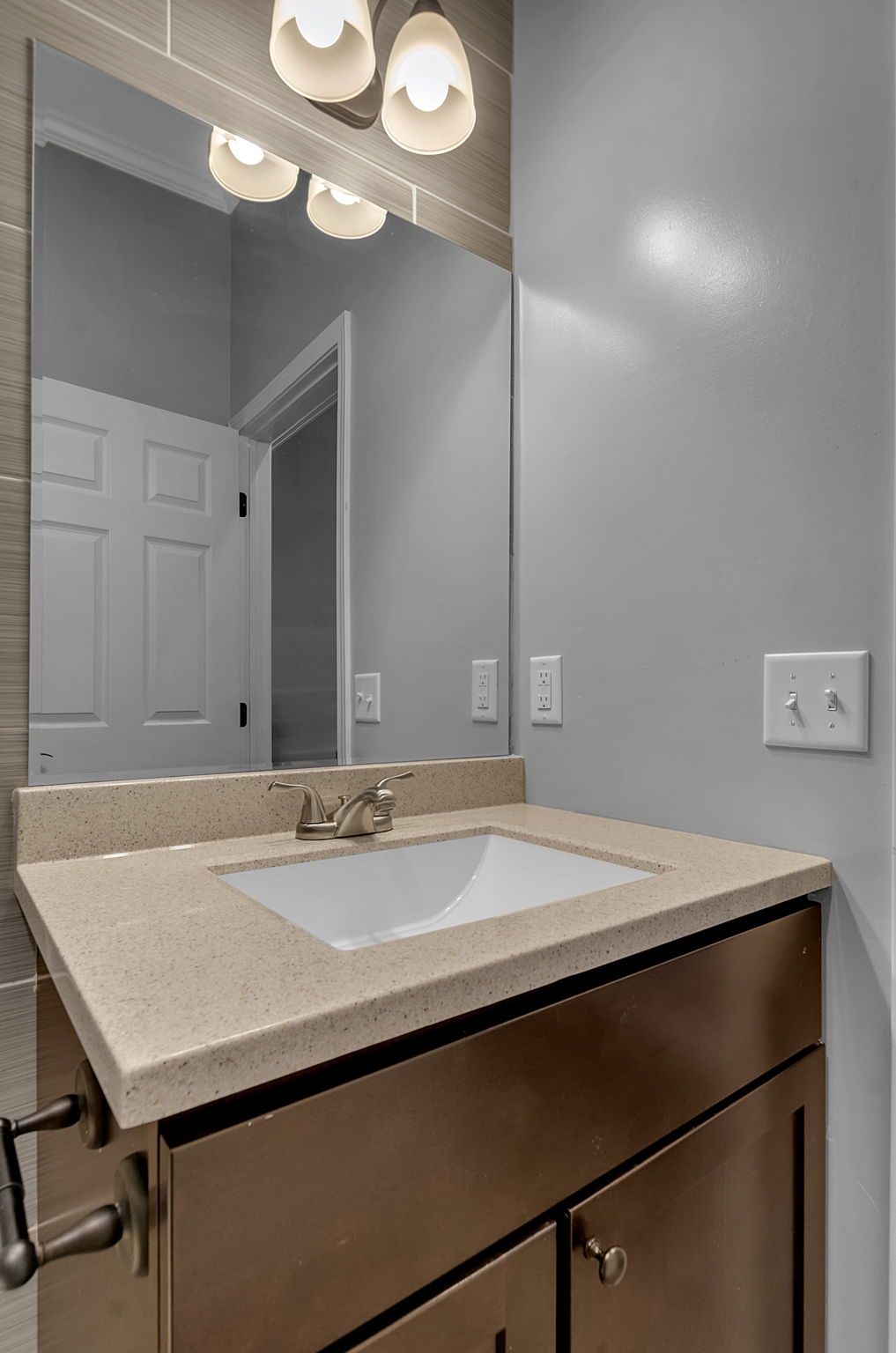 A bathroom with a sink , mirror and light fixtures.