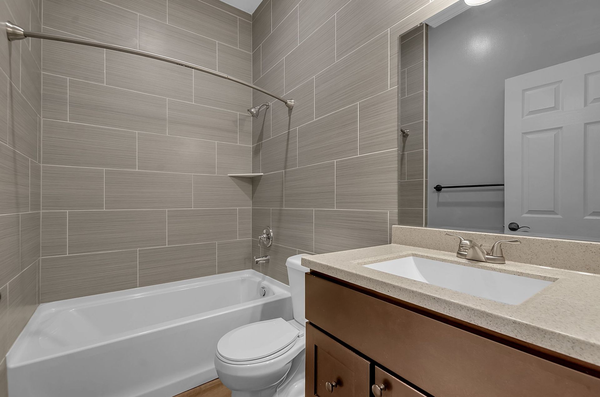 A bathroom with a toilet , sink , bathtub and mirror.