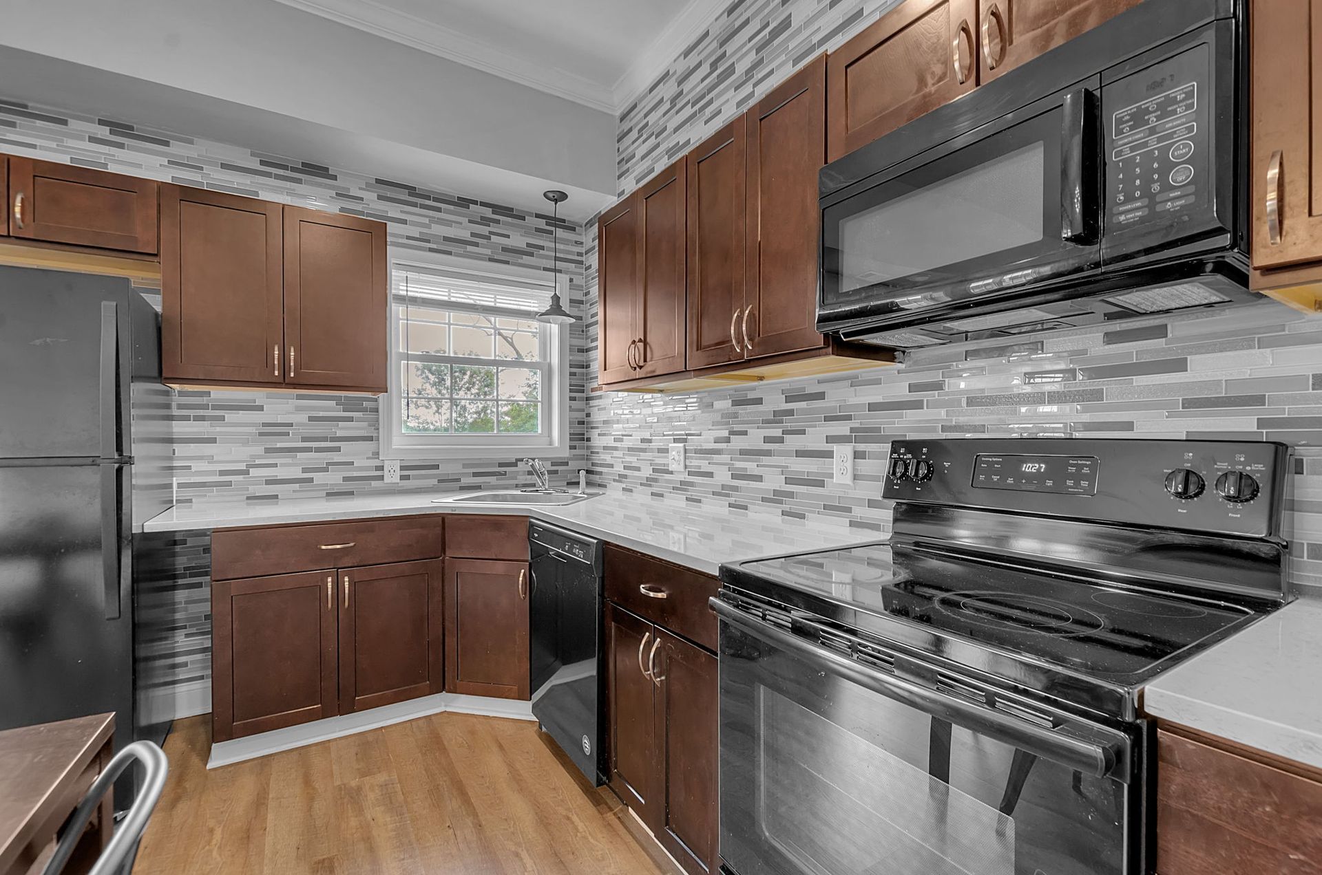 A kitchen with wooden cabinets , stainless steel appliances , a refrigerator and a microwave.