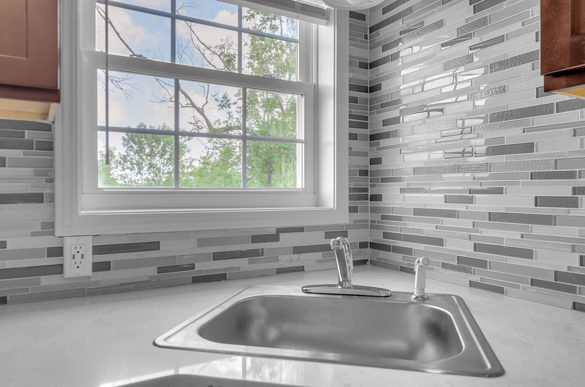 A kitchen with a stainless steel sink and a window.