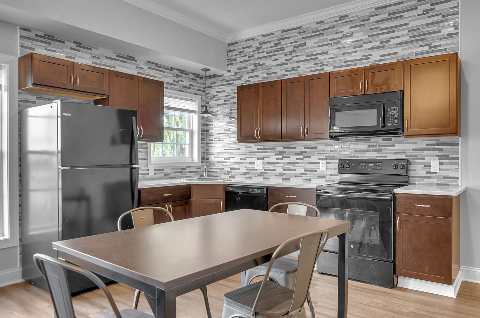 A kitchen with a table , chairs , refrigerator , stove and microwave.