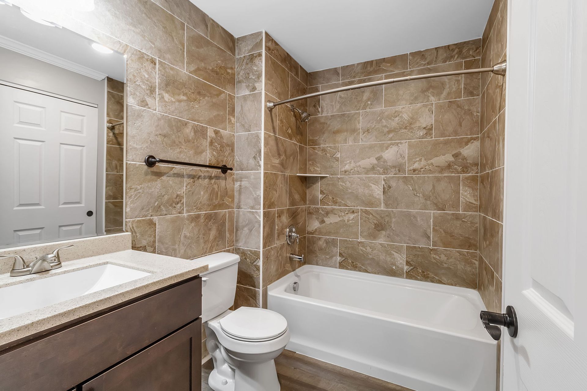A bathroom with a toilet , sink , bathtub and mirror.