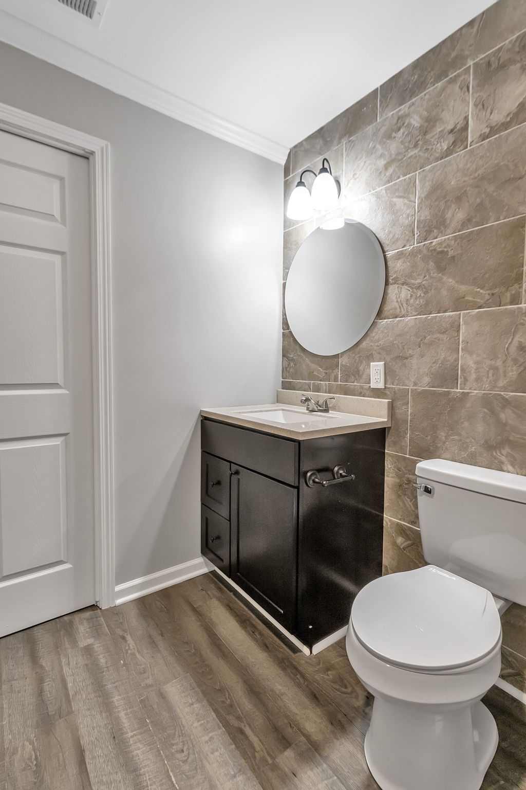 A bathroom with a toilet , sink and mirror.