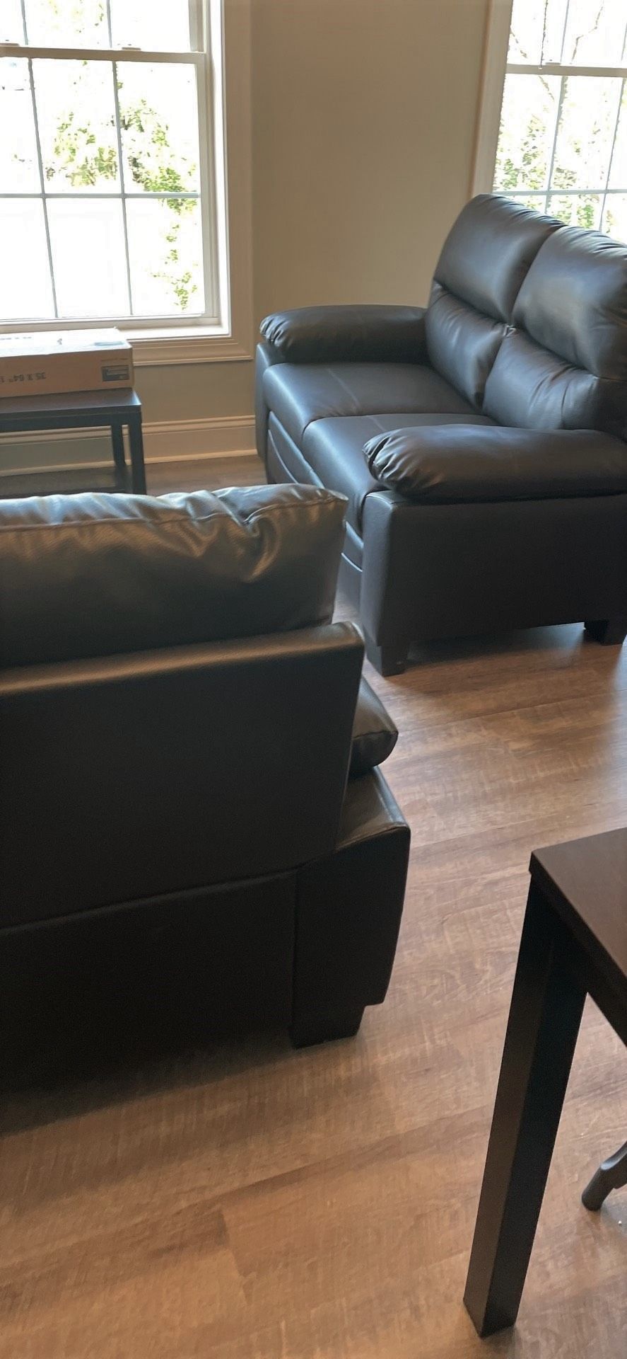 A living room with two black leather couches and a table.