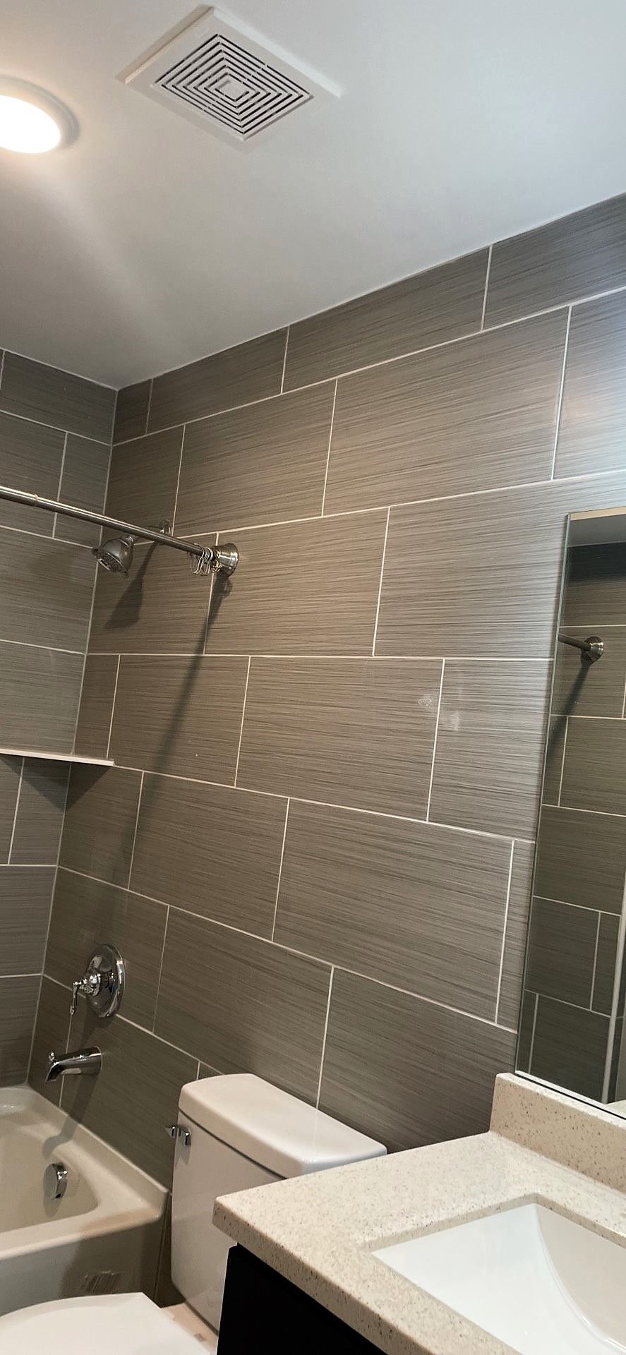 A bathroom with a sink , toilet , shower and mirror.