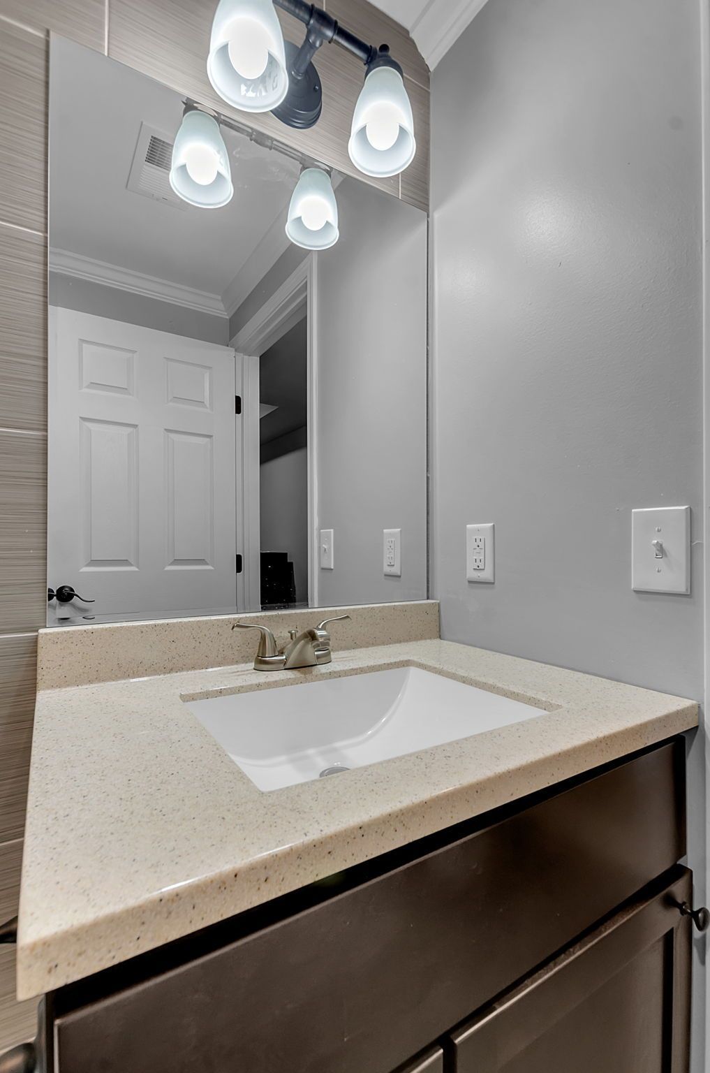 A bathroom with a sink , mirror and lights.