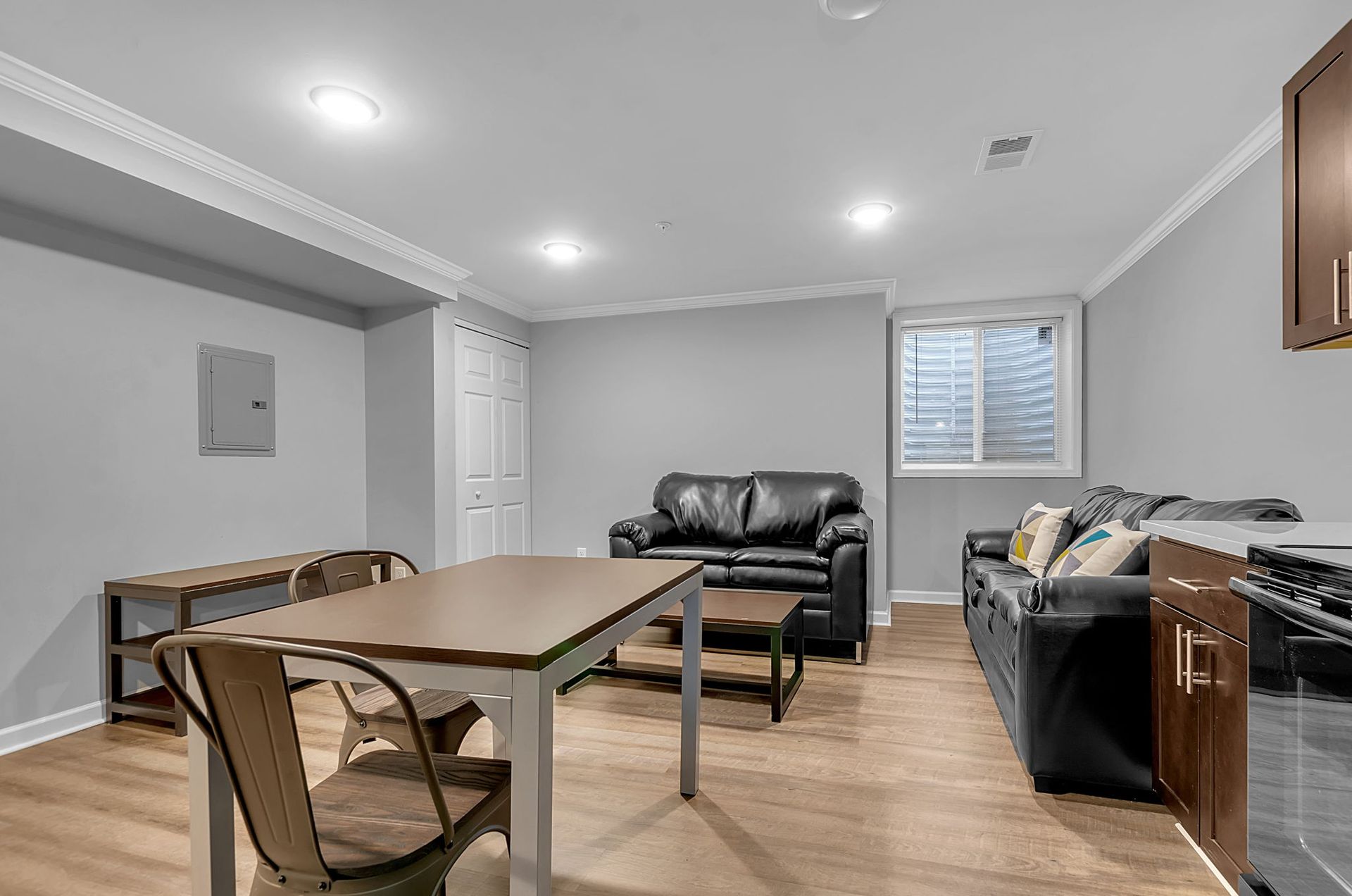 A living room with a couch , table , chairs and a window.