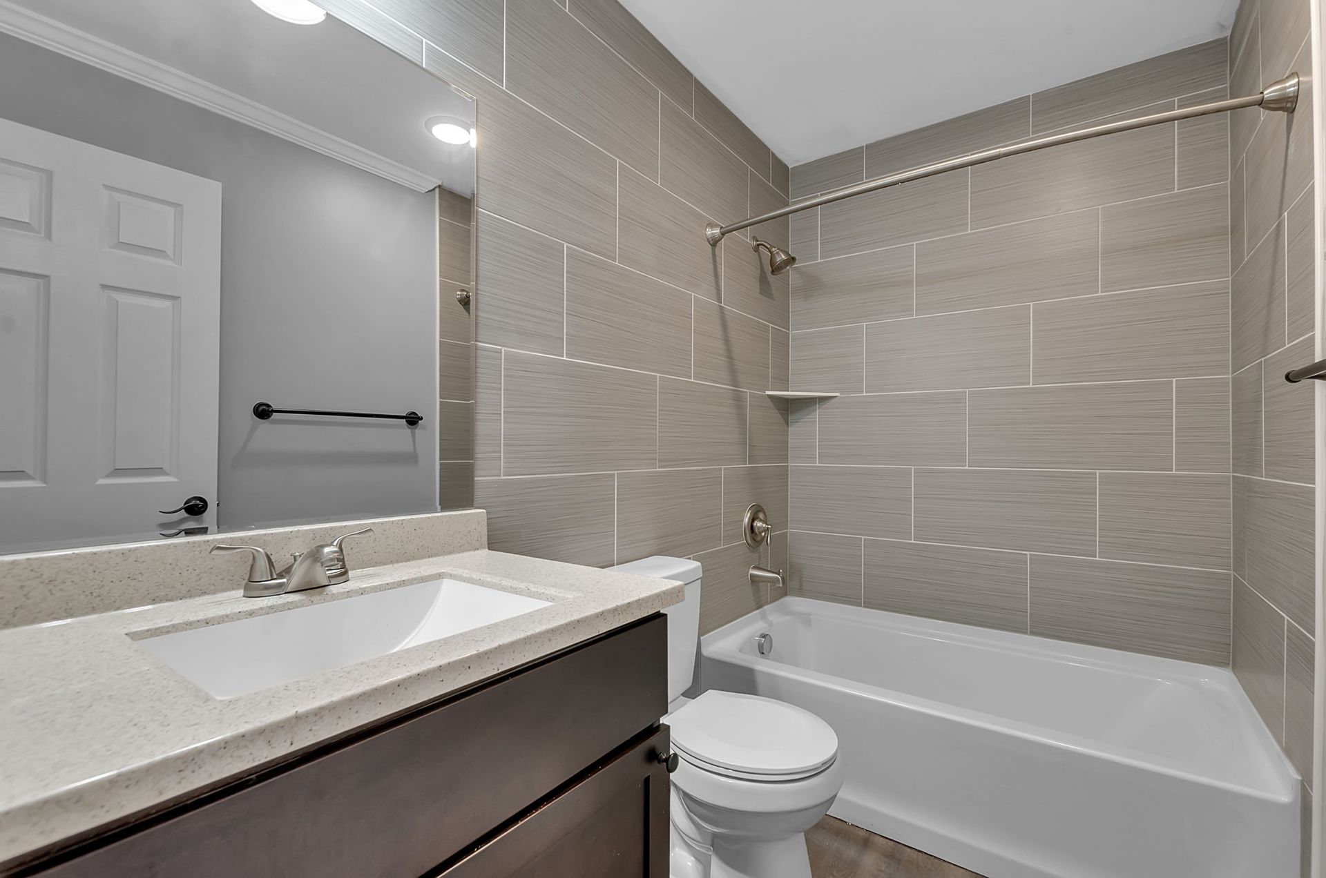 A bathroom with a toilet , sink , tub and mirror.
