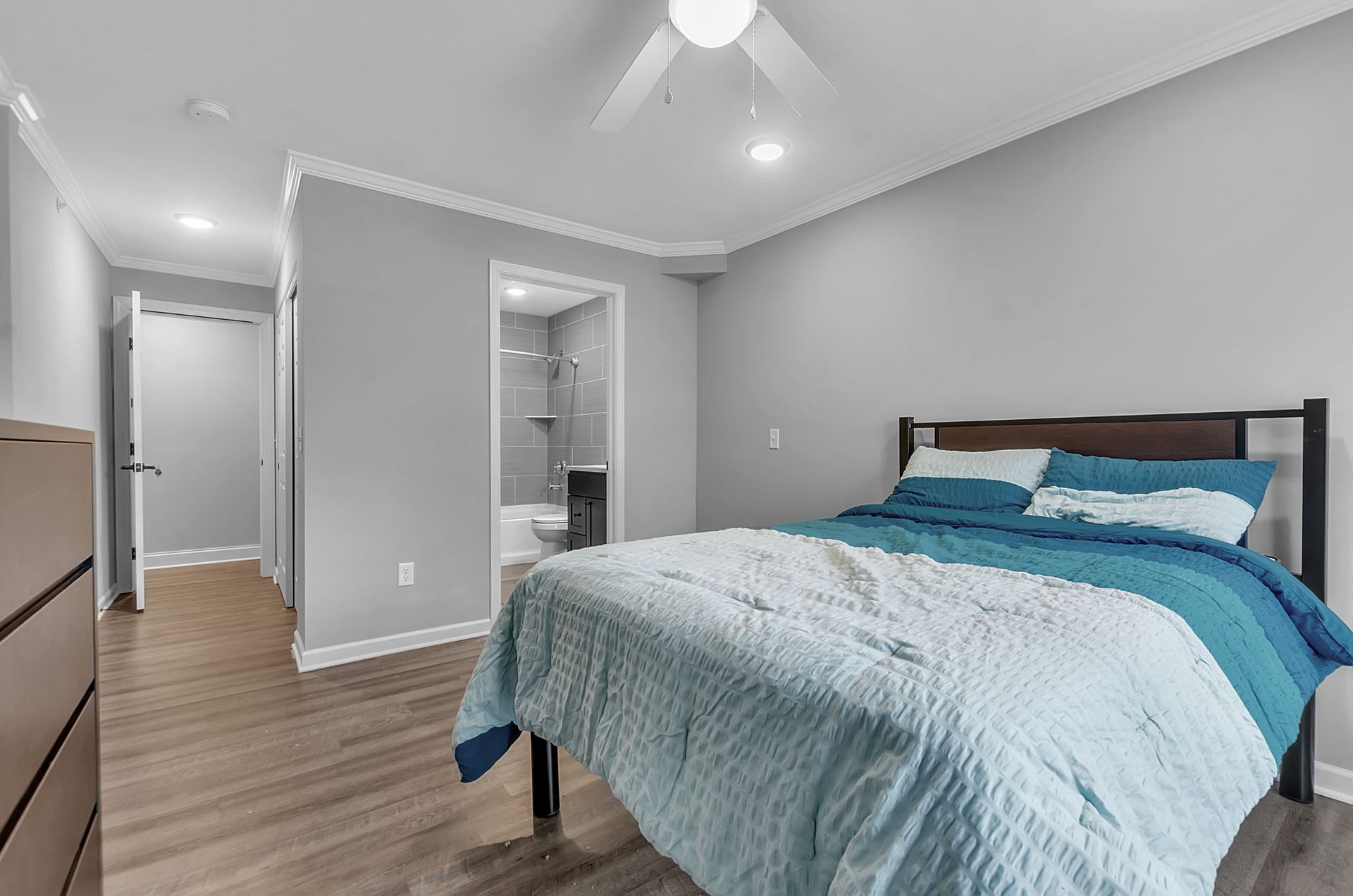 A bedroom with a bed , dresser , and ceiling fan.