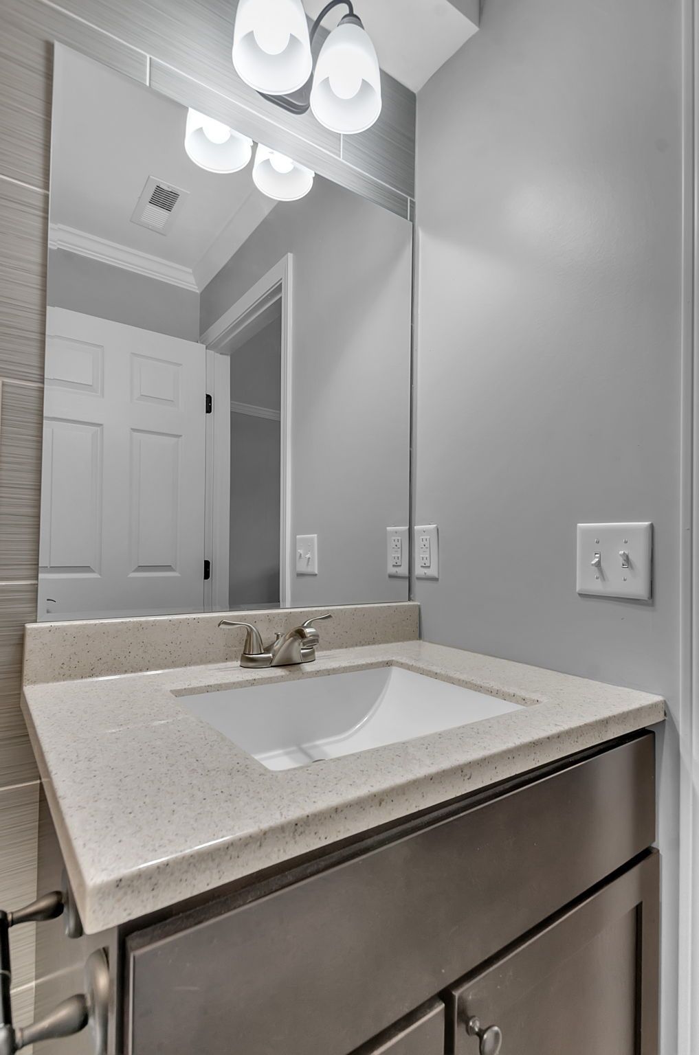 A bathroom with a sink , mirror and stainless steel cabinets.