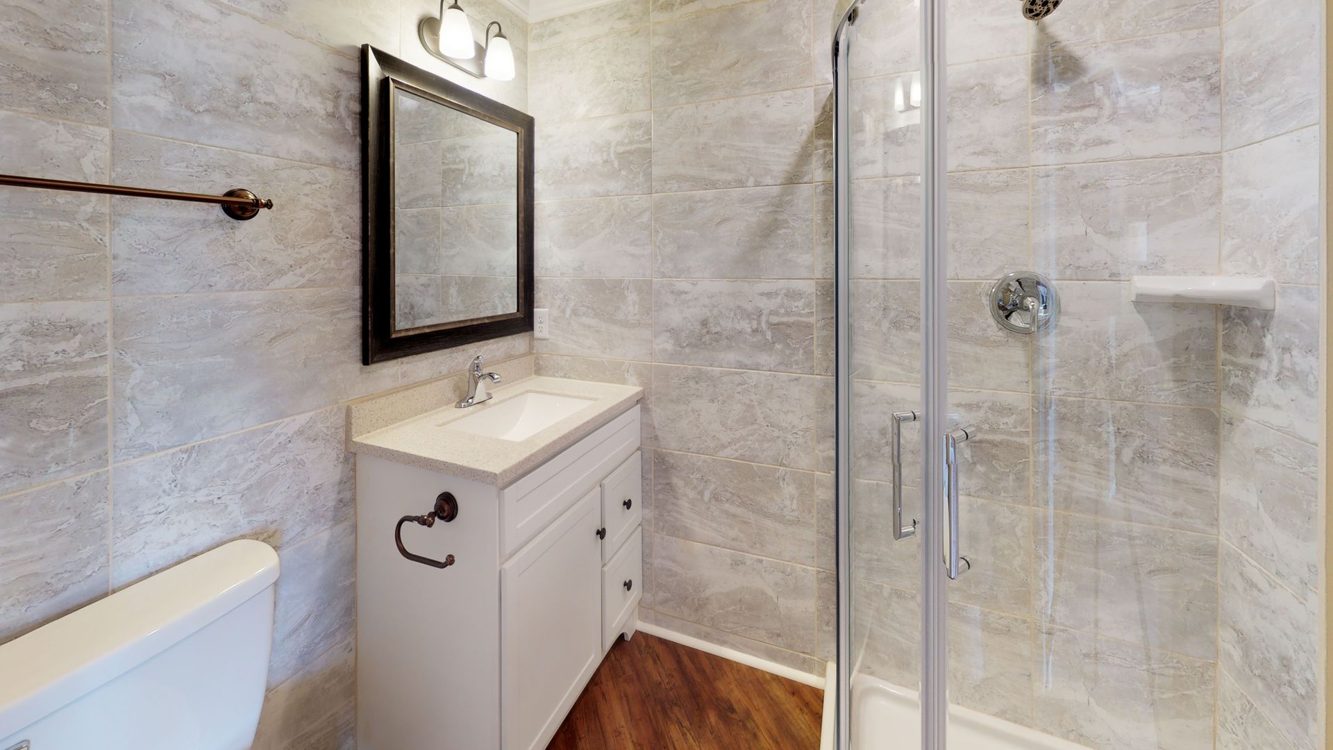 A bathroom with a toilet , sink , mirror and walk in shower.