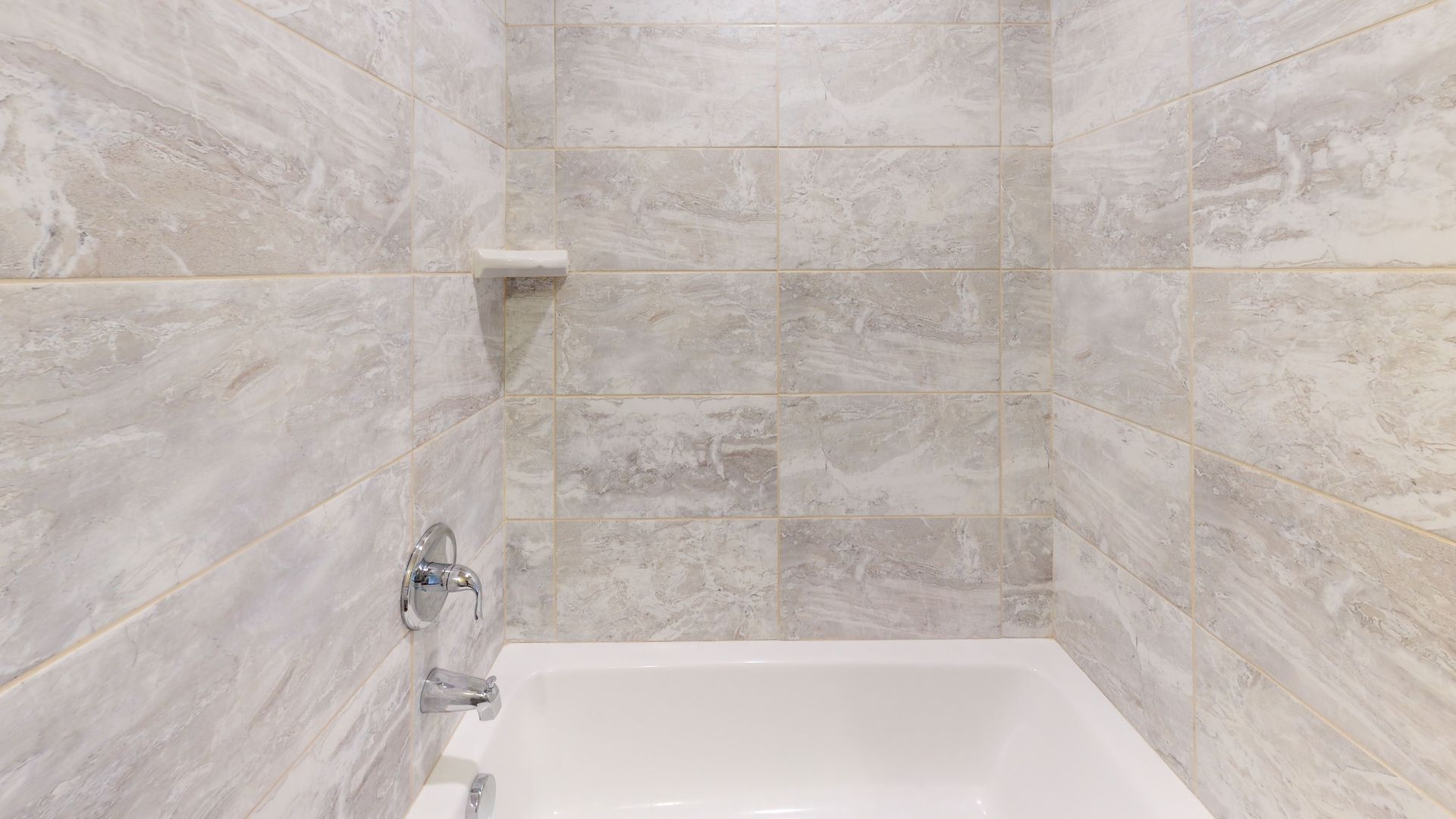 A bathroom with a bathtub , shower , and tiled walls.