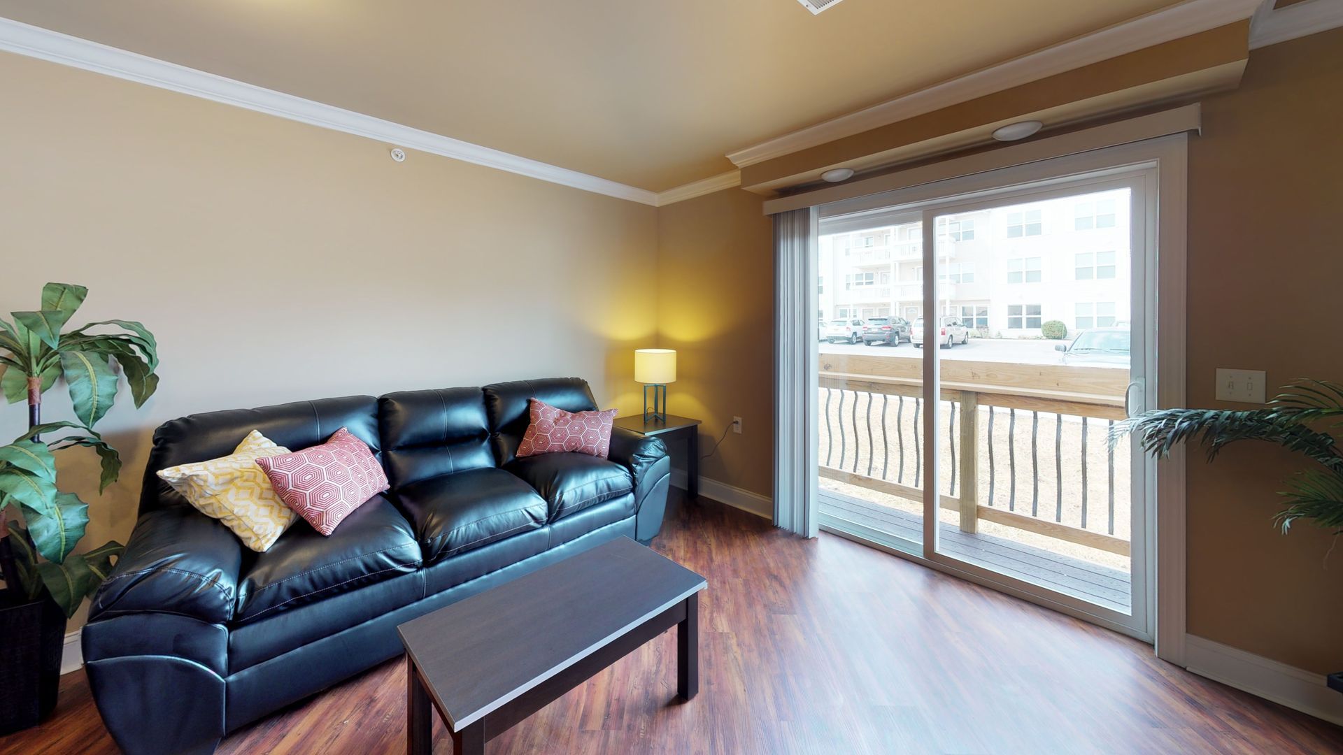A living room with a couch , coffee table , and sliding glass doors leading to a balcony.