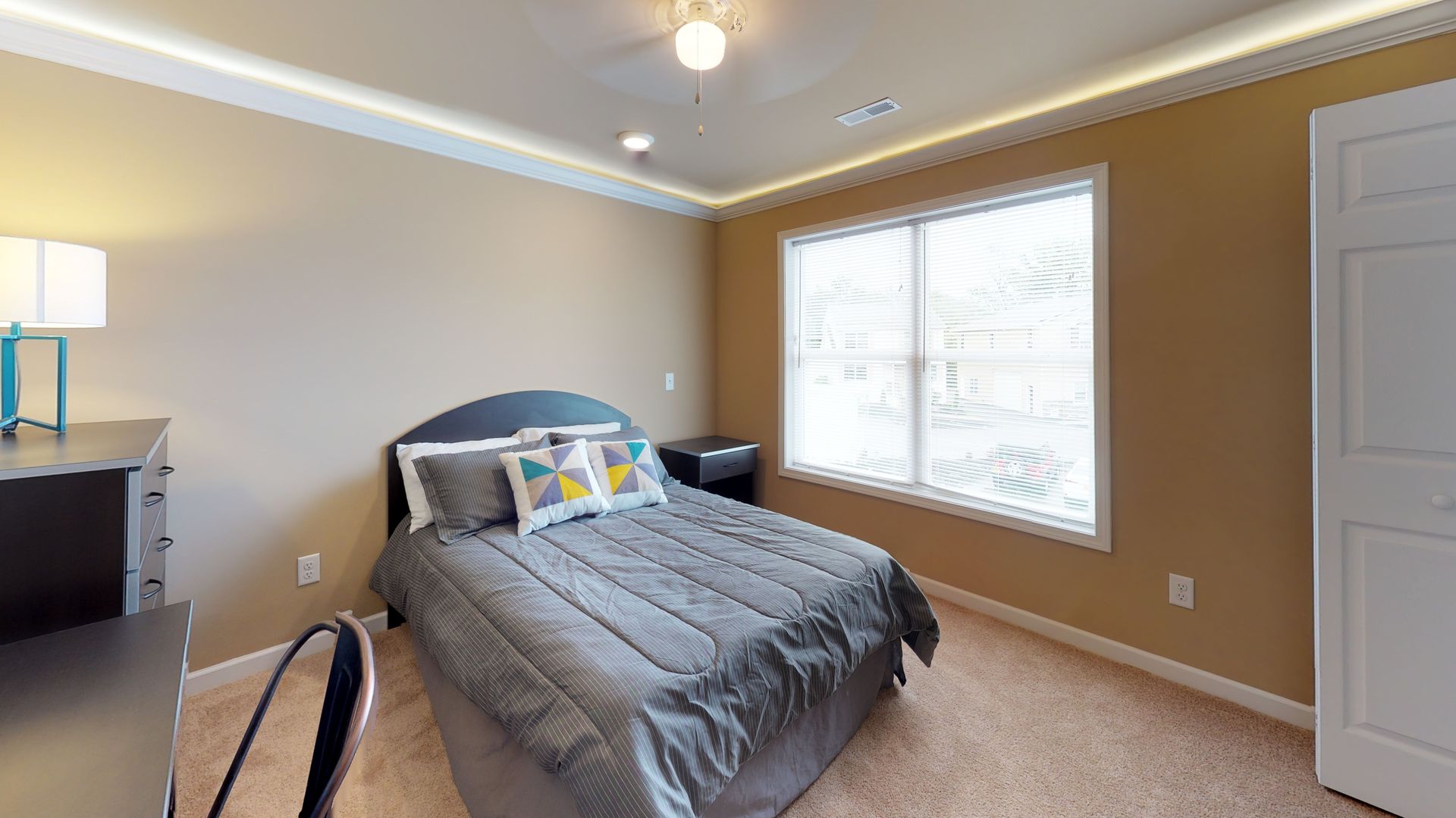 A bedroom with a bed , desk , and window.