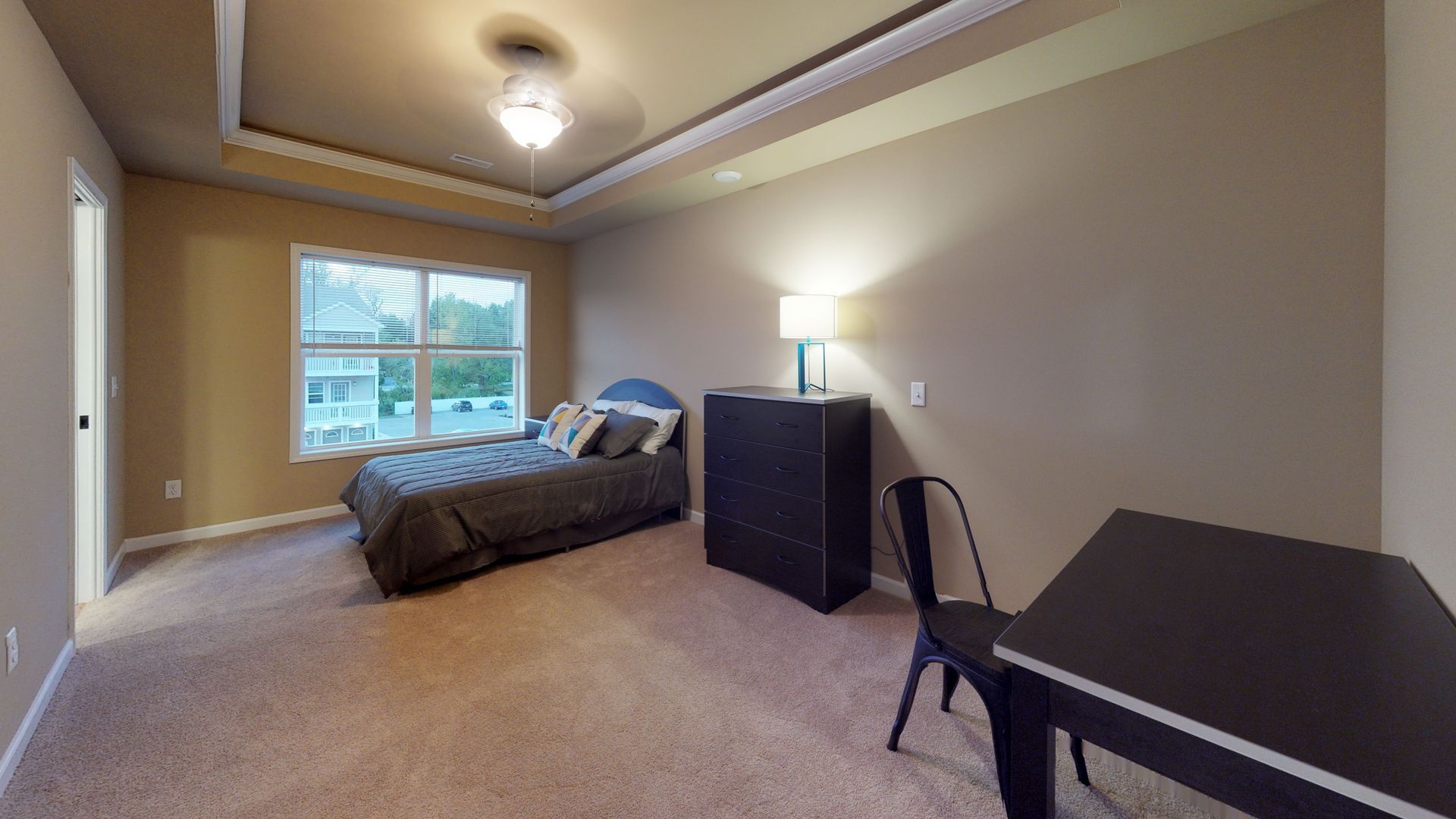 A bedroom with a bed , desk , chair and dresser.