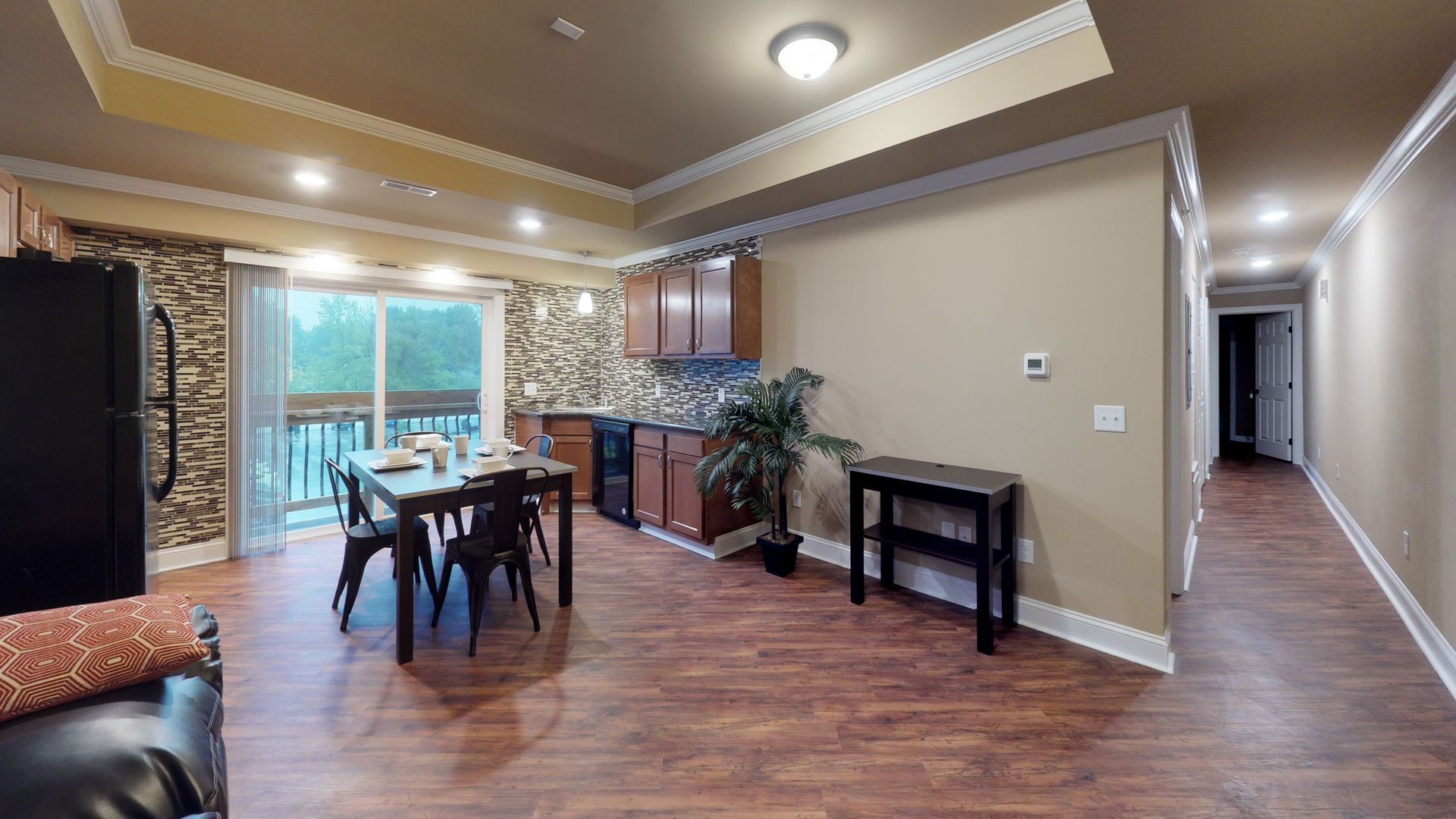 A living room with hardwood floors , a dining room table and chairs , a kitchen and a hallway.
