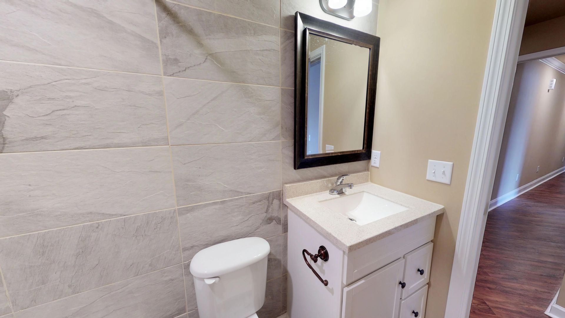 A bathroom with a toilet , sink and mirror.