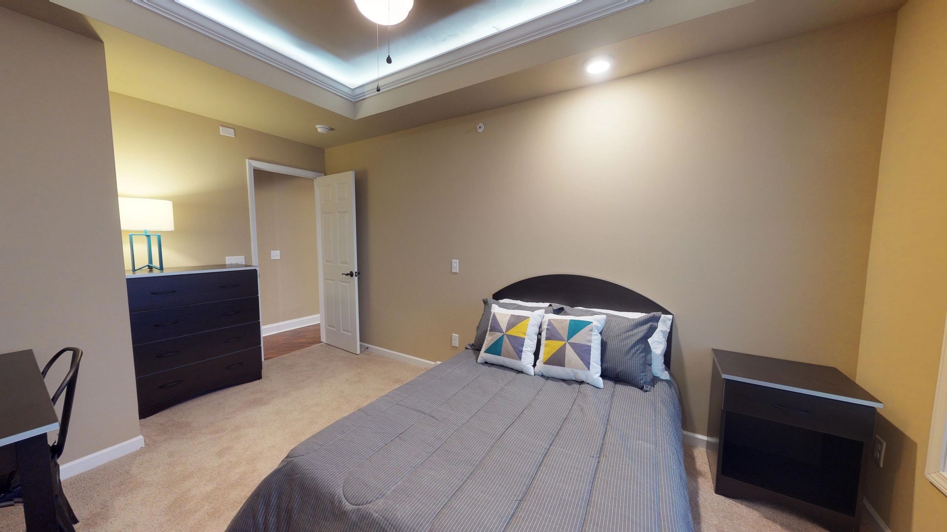 A bedroom with a bed , nightstand , desk and dresser.