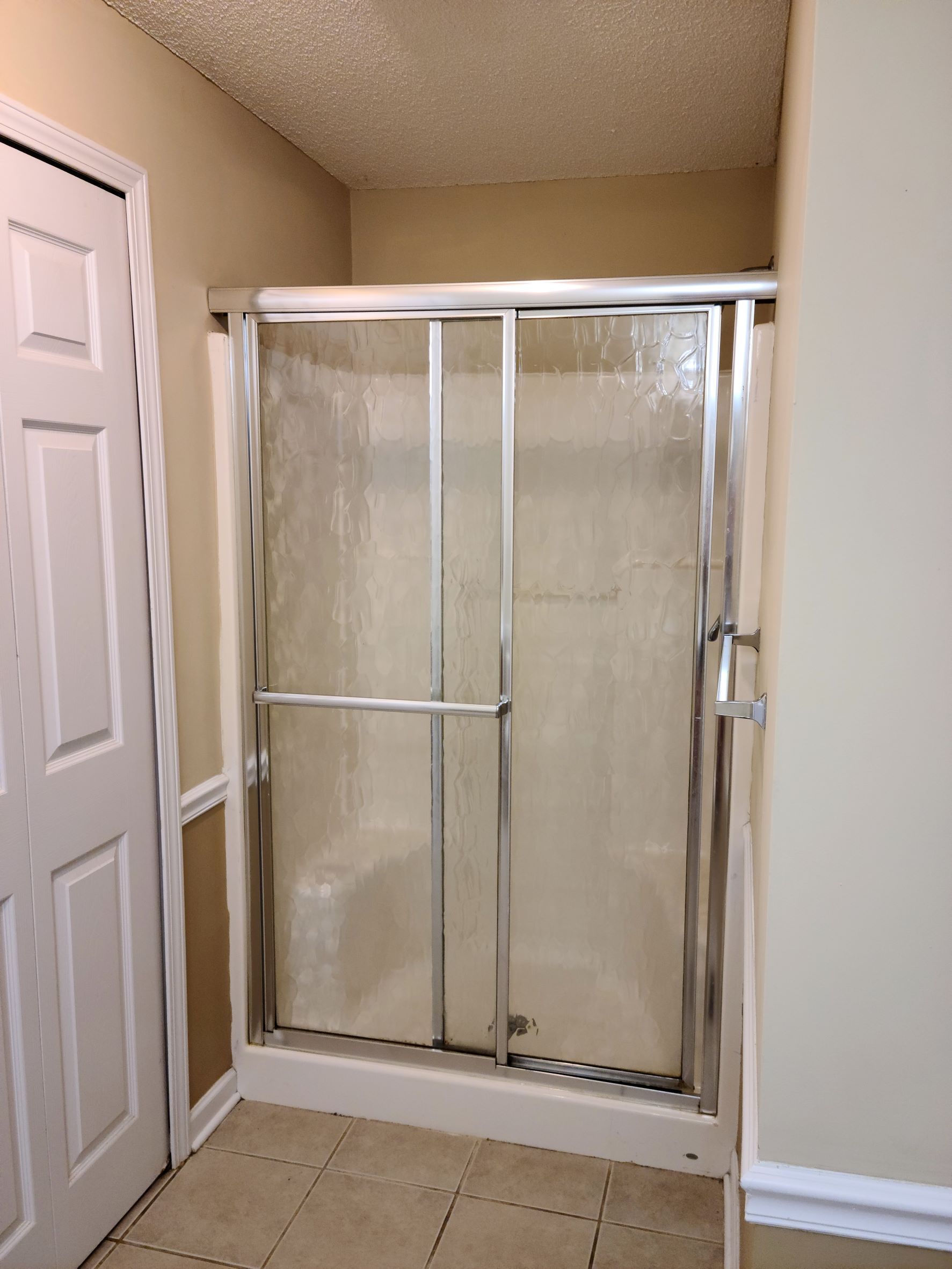 A bathroom with a sliding glass shower door
