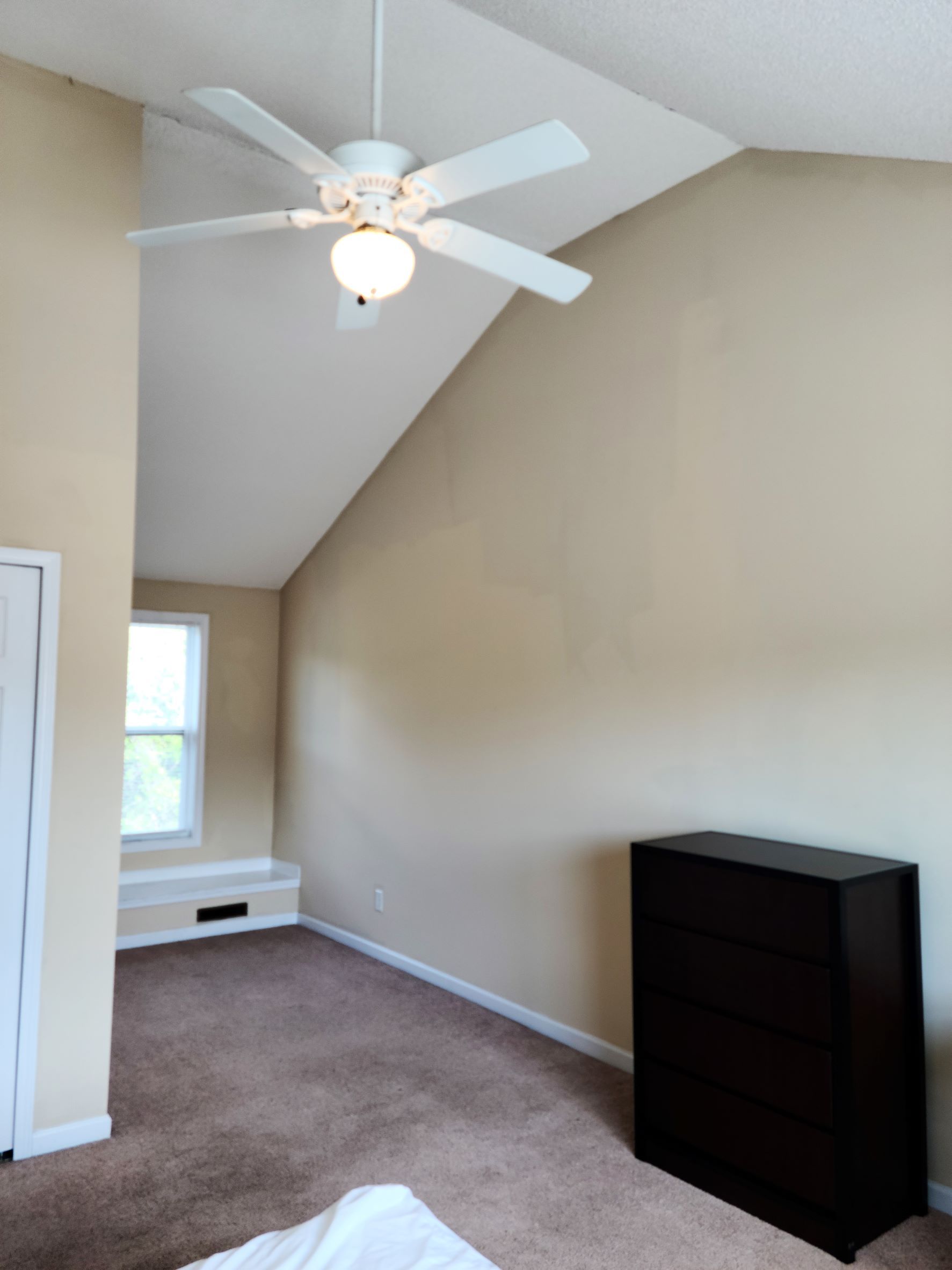A bedroom with a vaulted ceiling and a ceiling fan