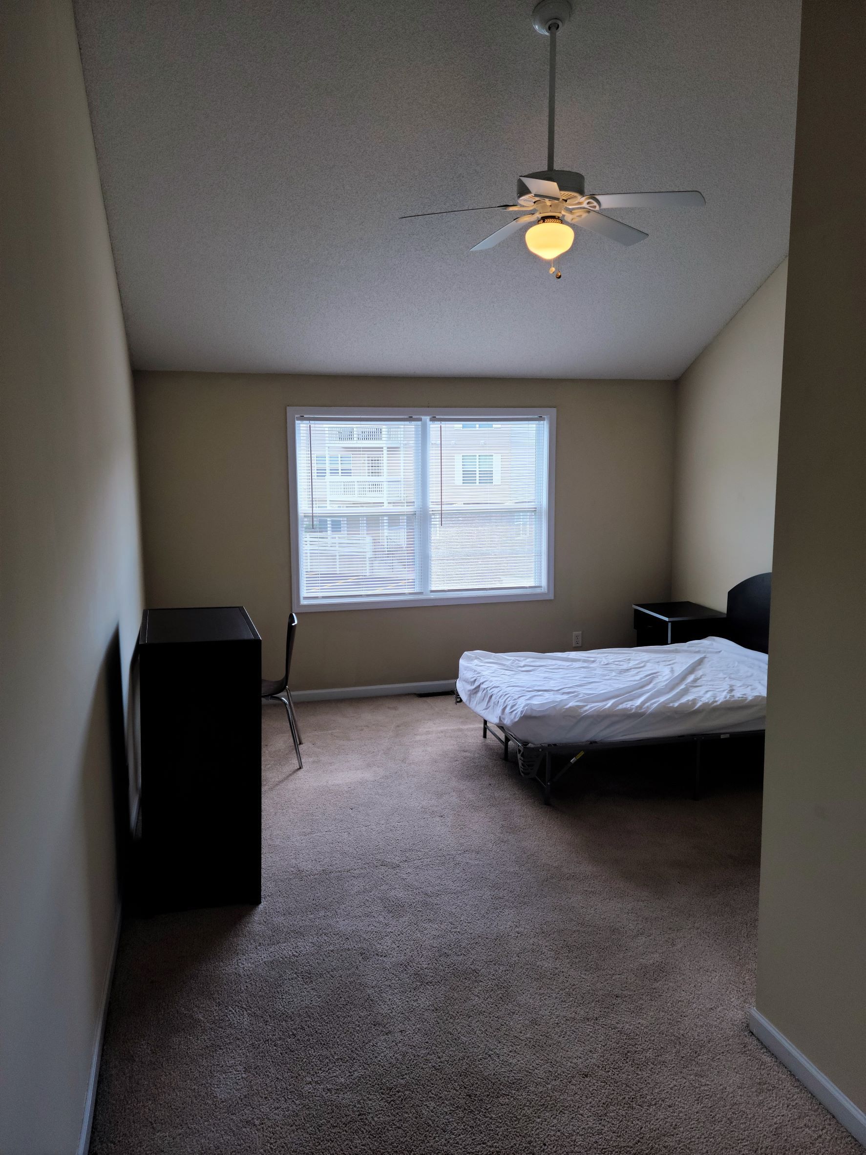 A bedroom with a bed and a ceiling fan