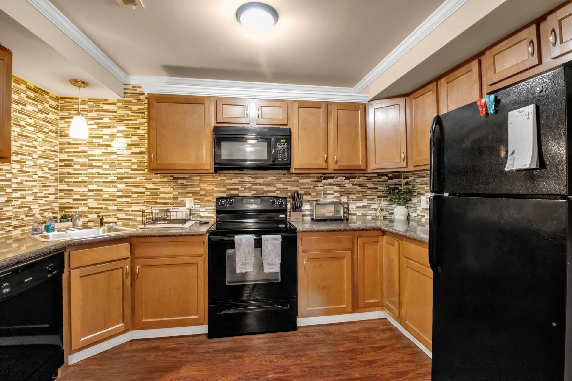 A kitchen with wooden cabinets and a black refrigerator
