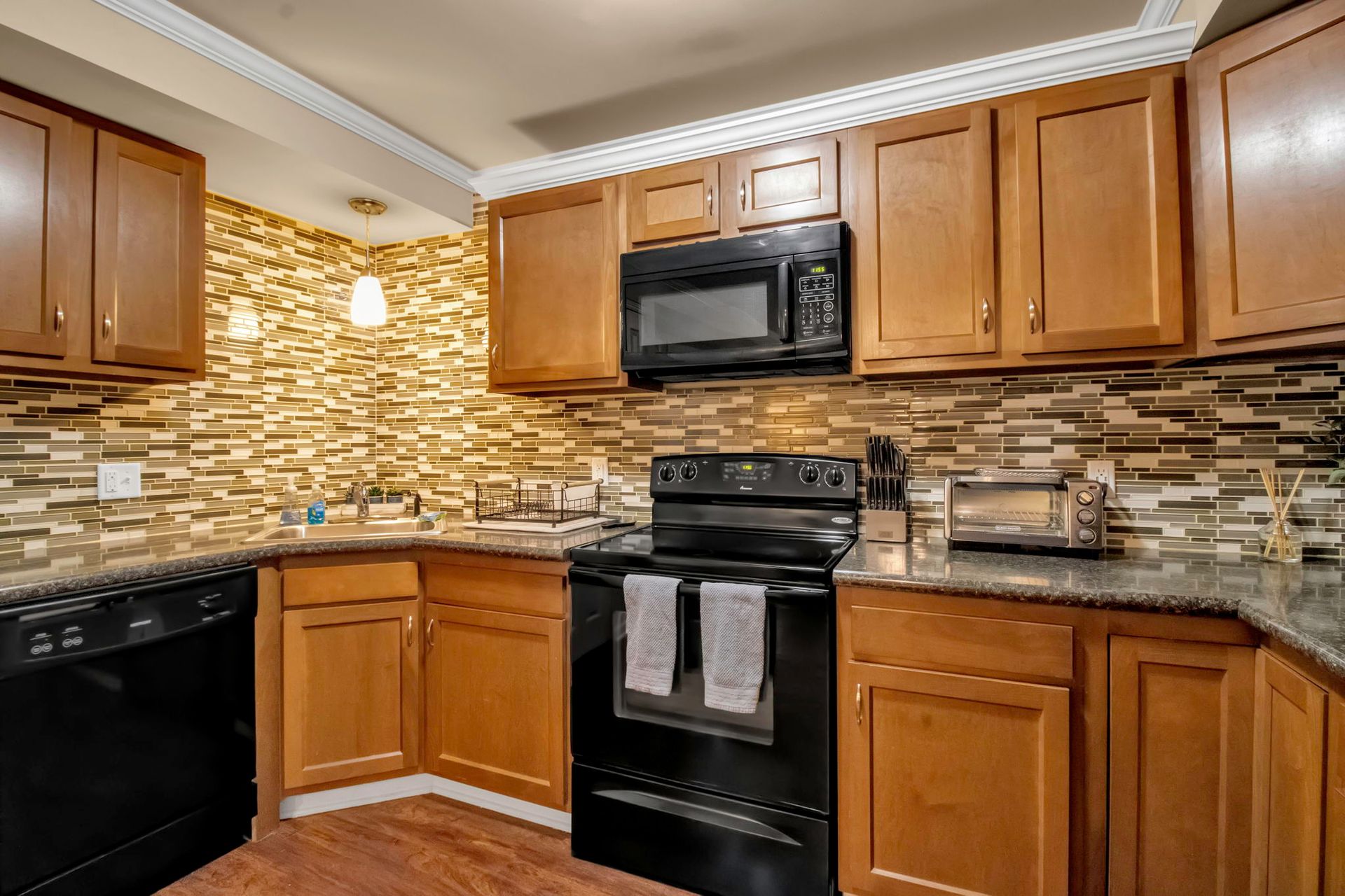 A kitchen with wooden cabinets , black appliances , a stove and a microwave.