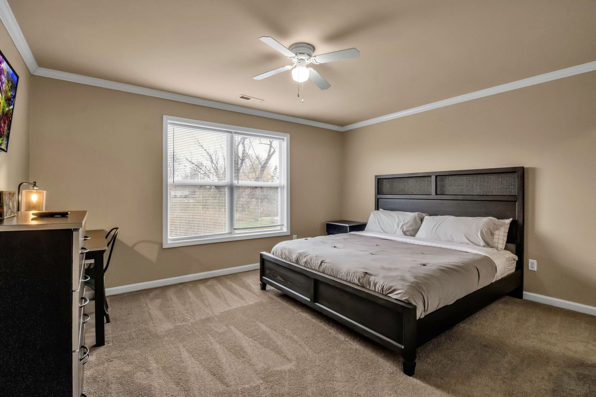 A bedroom with a king size bed and a ceiling fan.
