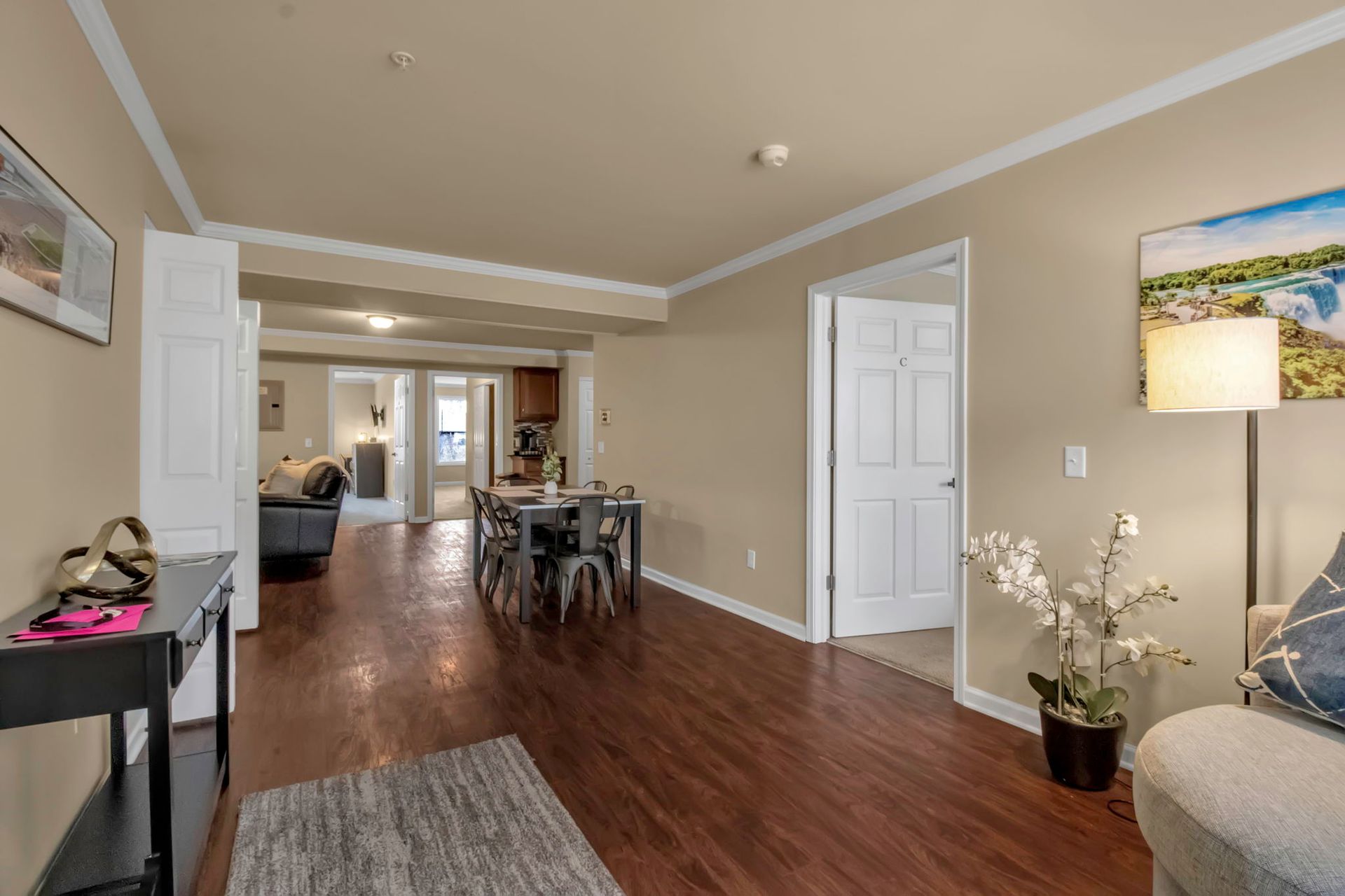 A living room with hardwood floors , a couch , a table and a lamp.