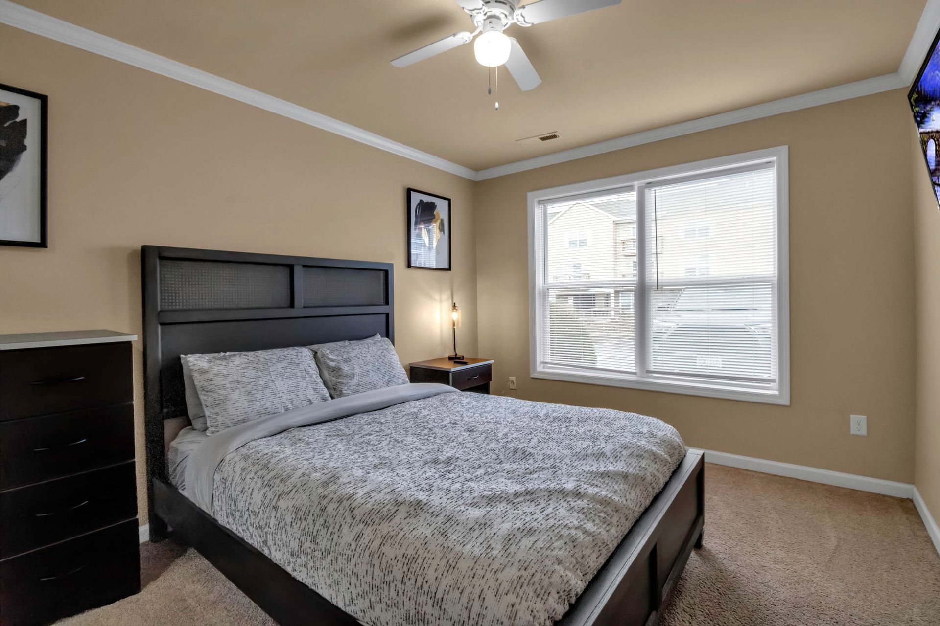 A bedroom with a bed , dresser , nightstand and ceiling fan.