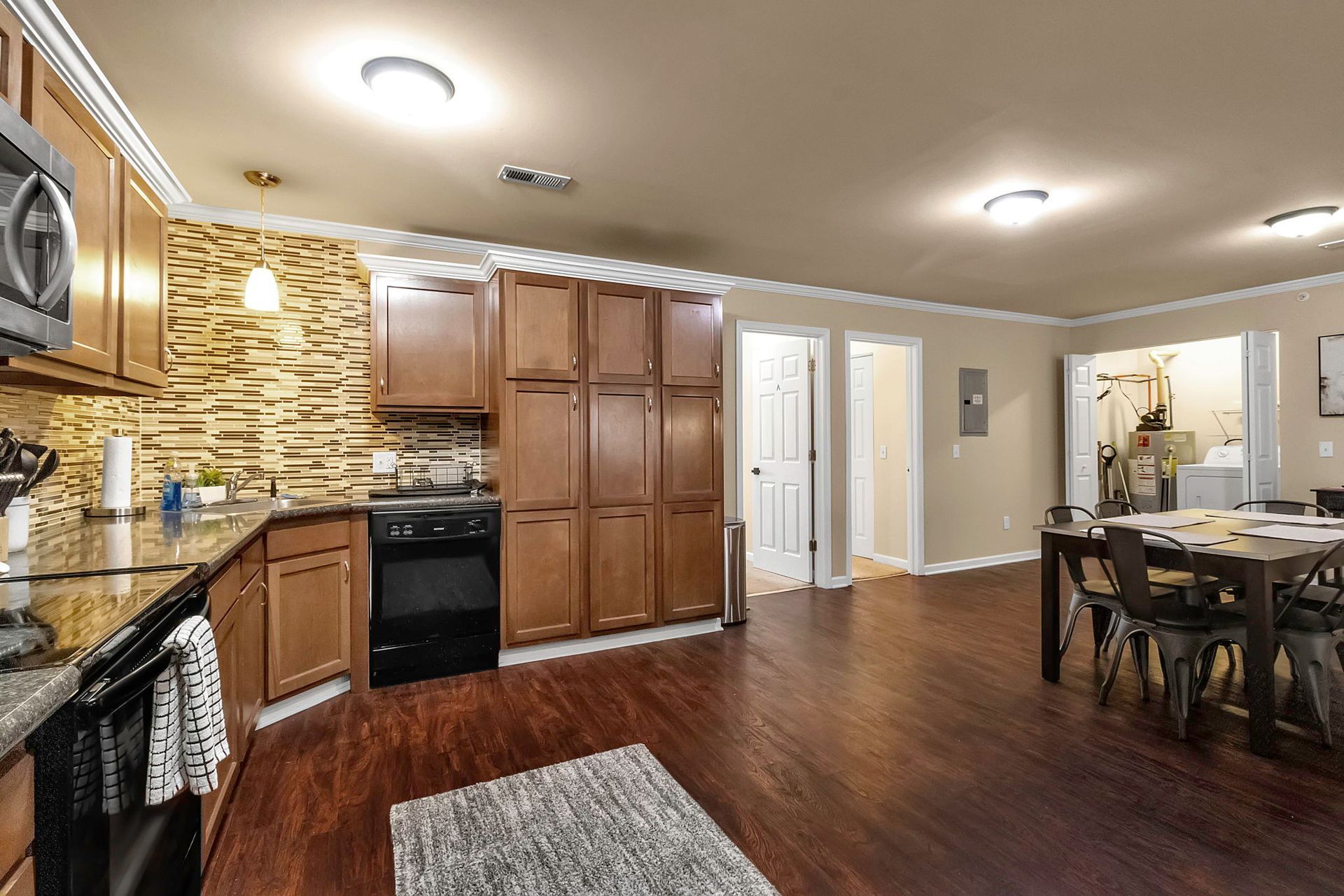A kitchen with wooden cabinets , granite counter tops , a stove and a table.