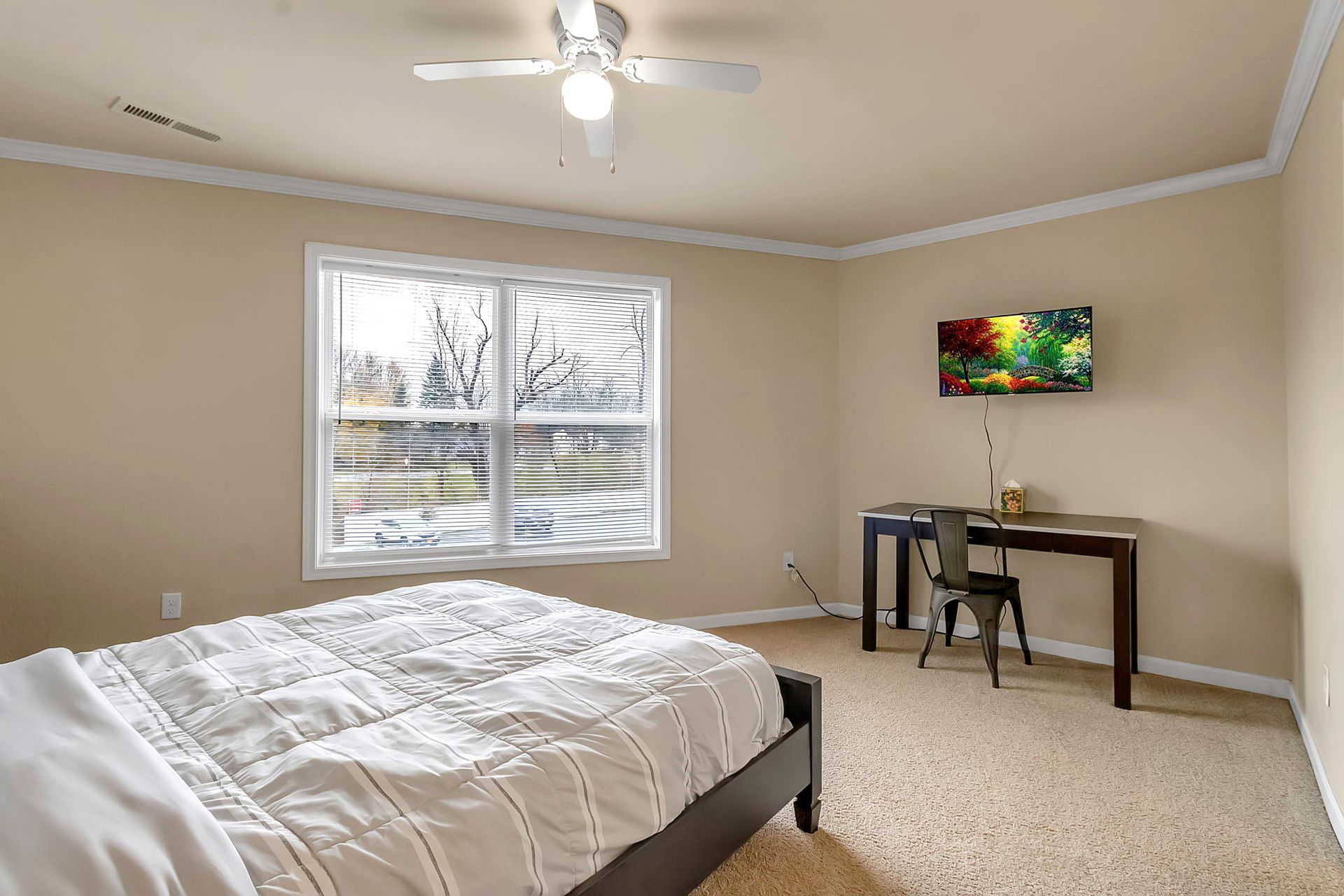 A bedroom with a bed , desk , chair and ceiling fan.