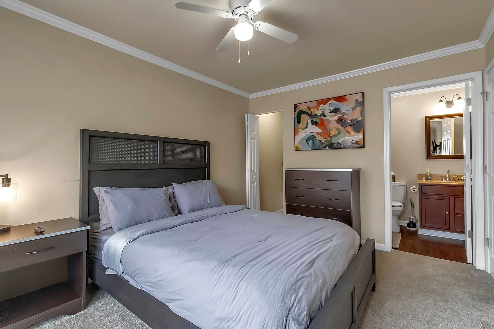 A bedroom with a king size bed and a ceiling fan.