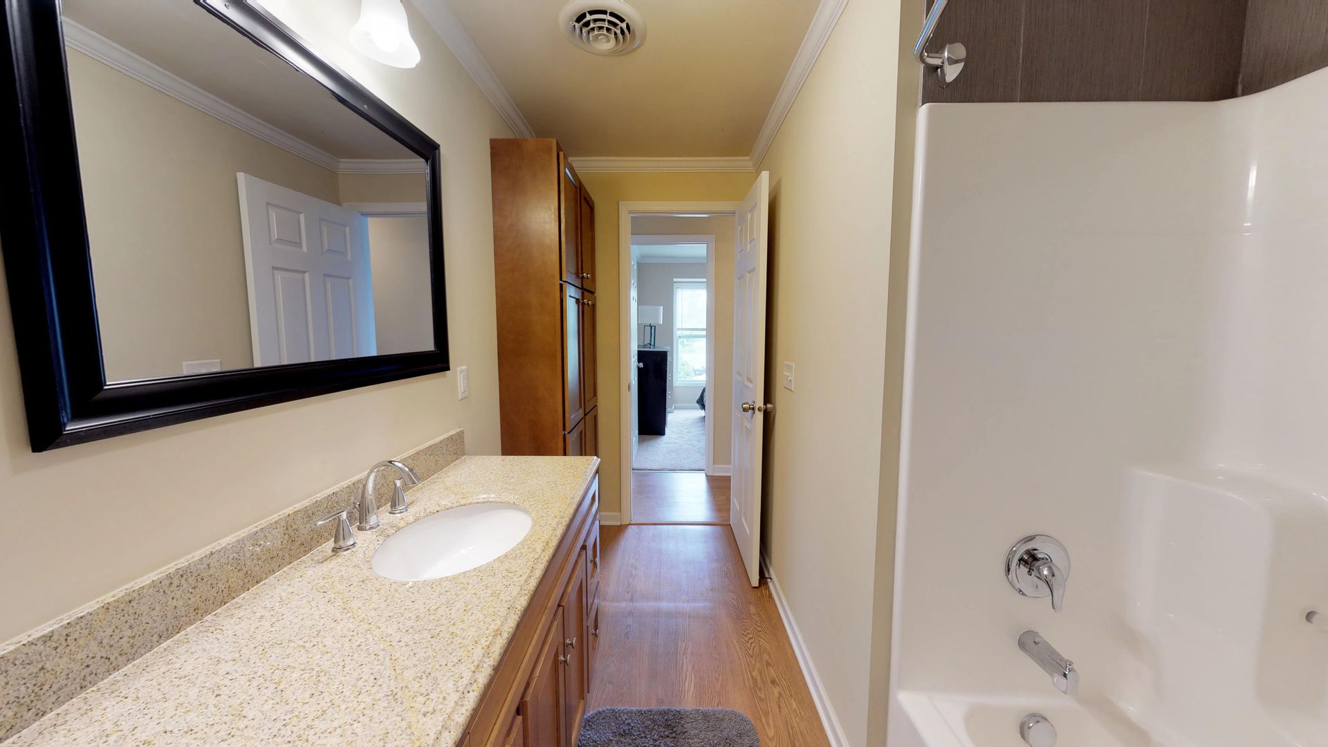 A bathroom with a tub , sink , mirror and shower.