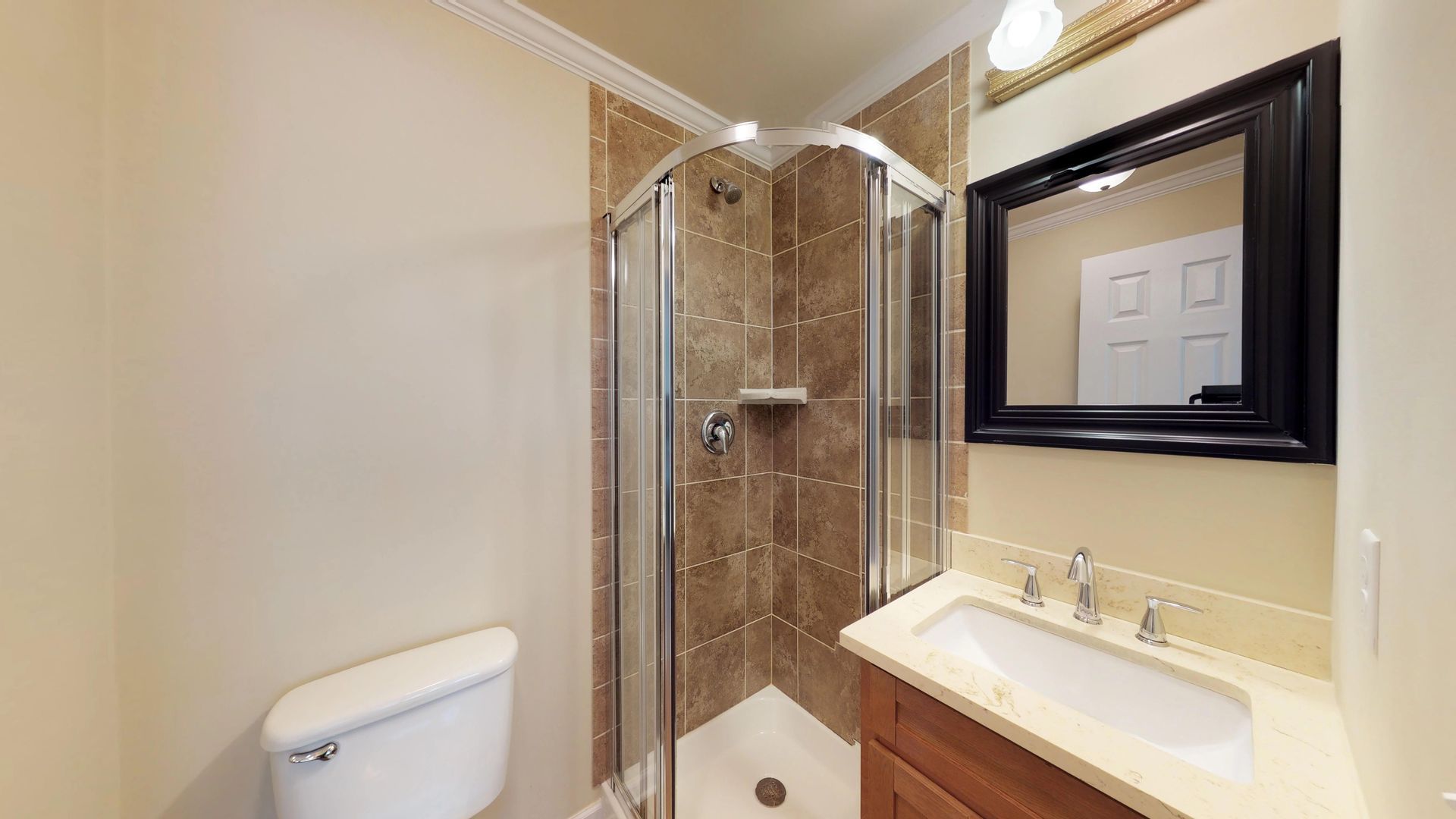 A bathroom with a toilet , sink , shower and mirror.